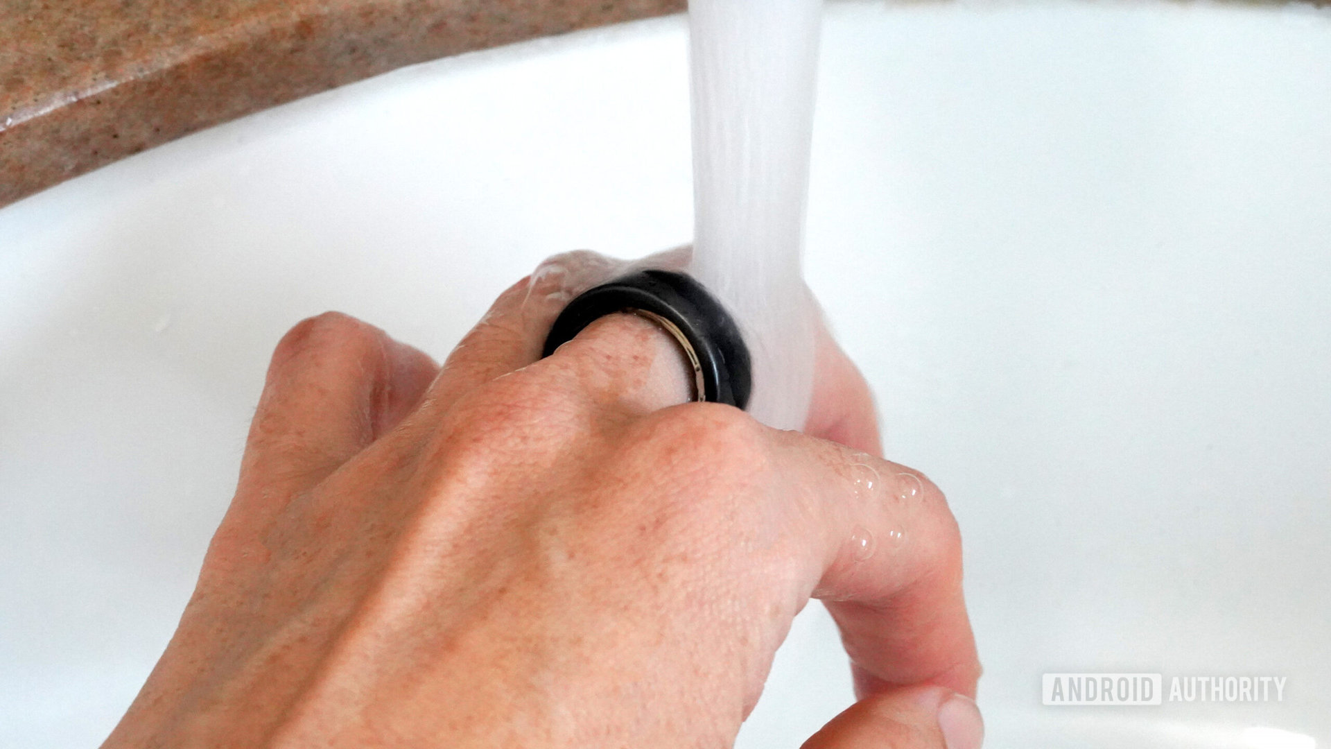 Seorang pengguna Oura Ring 3 mencuci tangannya dengan perangkat menyala.