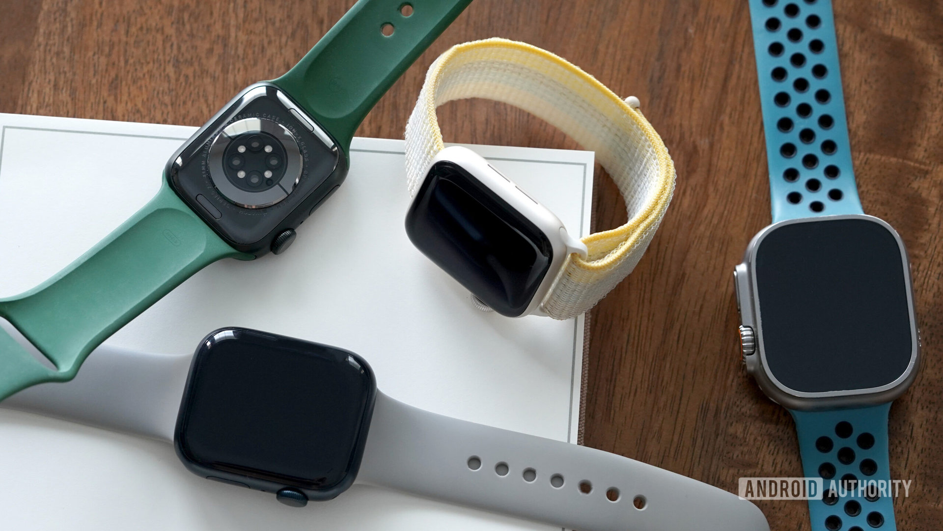 A variety of Apple Watches rest on a desk.