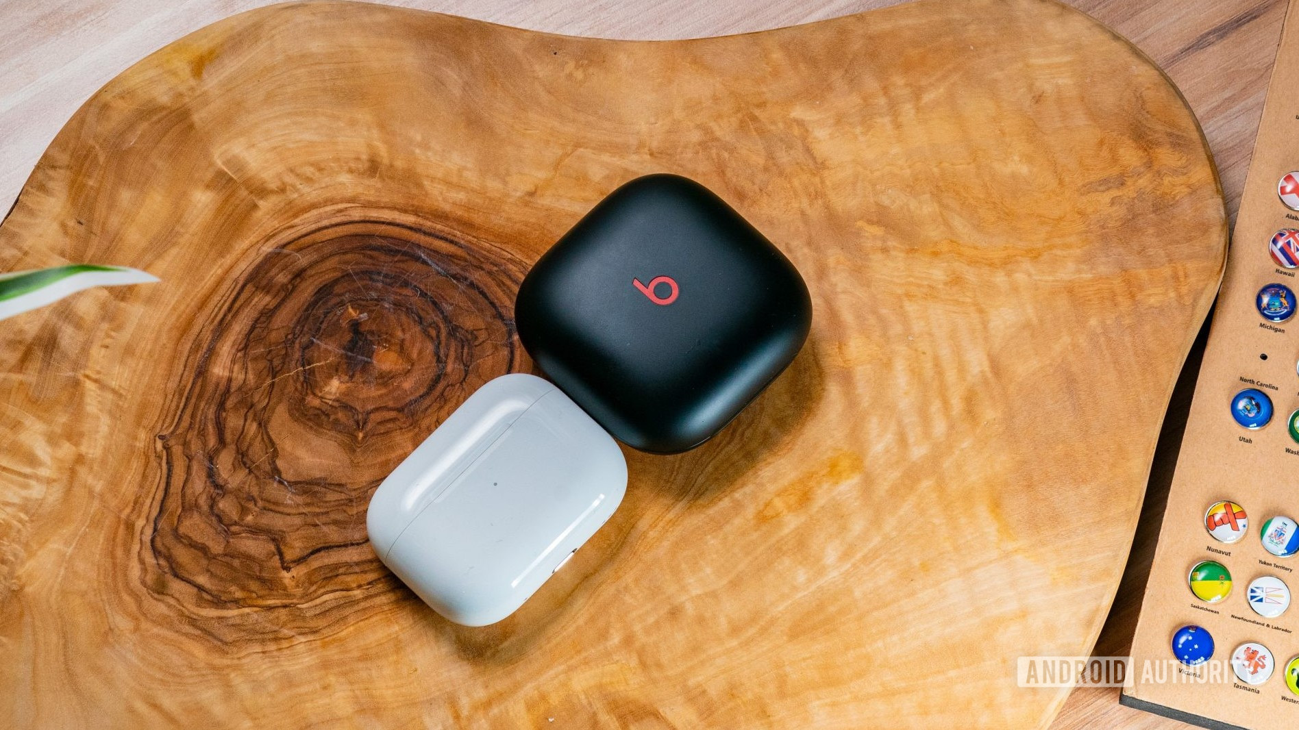 The Beats Fit Pro and AirPods Pro (2nd generation) cases side by side on a wood surface.