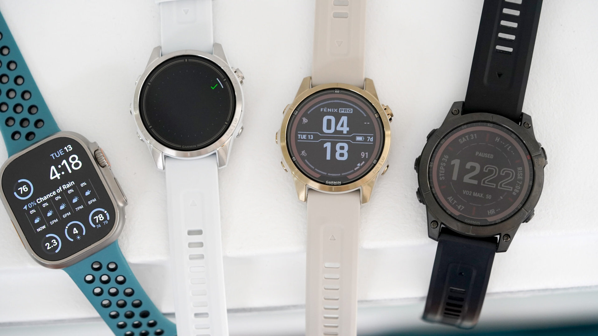A variety of leading multisport watches rest on a white shelf.