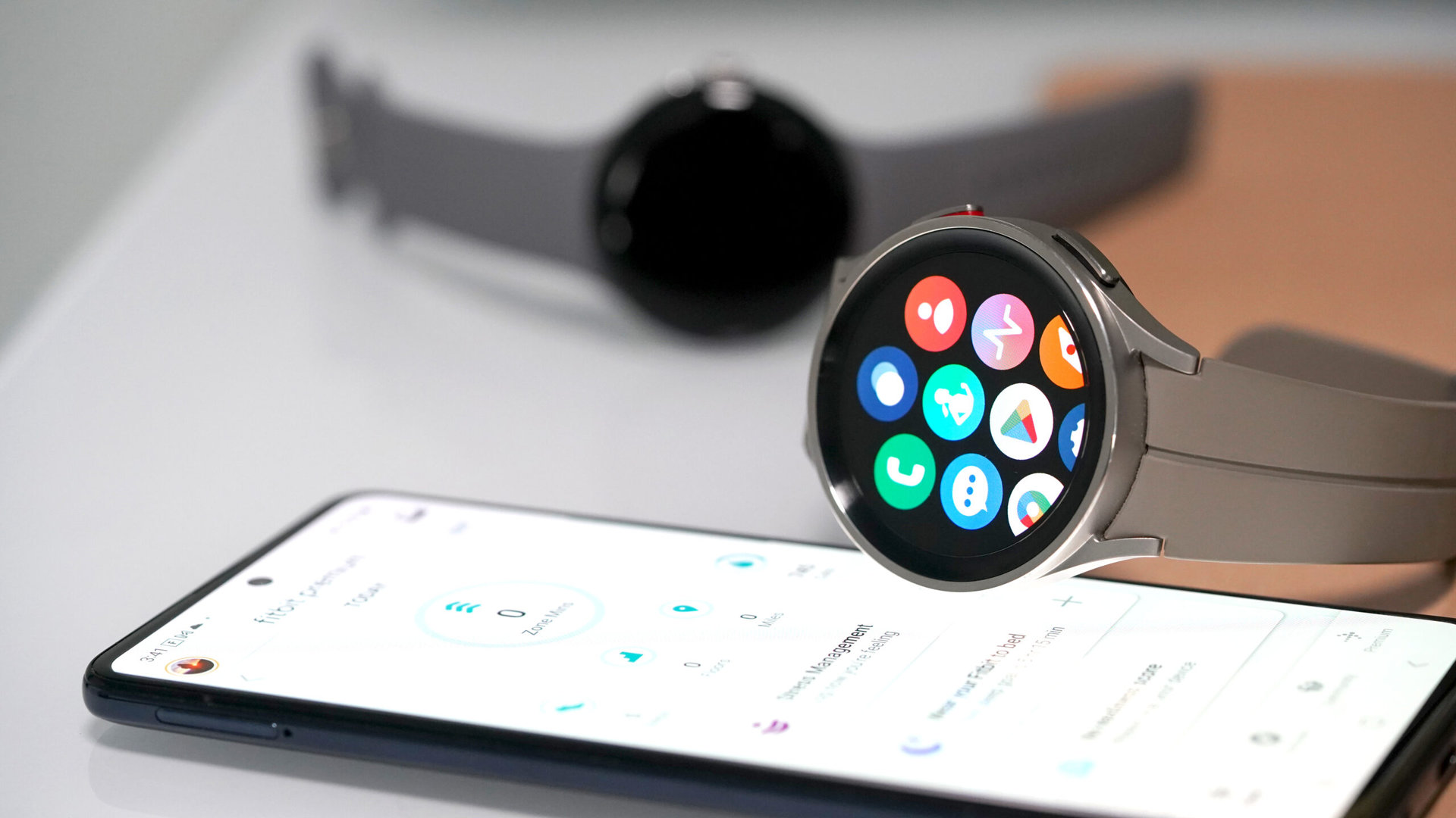 A Samsung Galaxy Watch 5 rests alongside a Pixel Watch and Android phone.