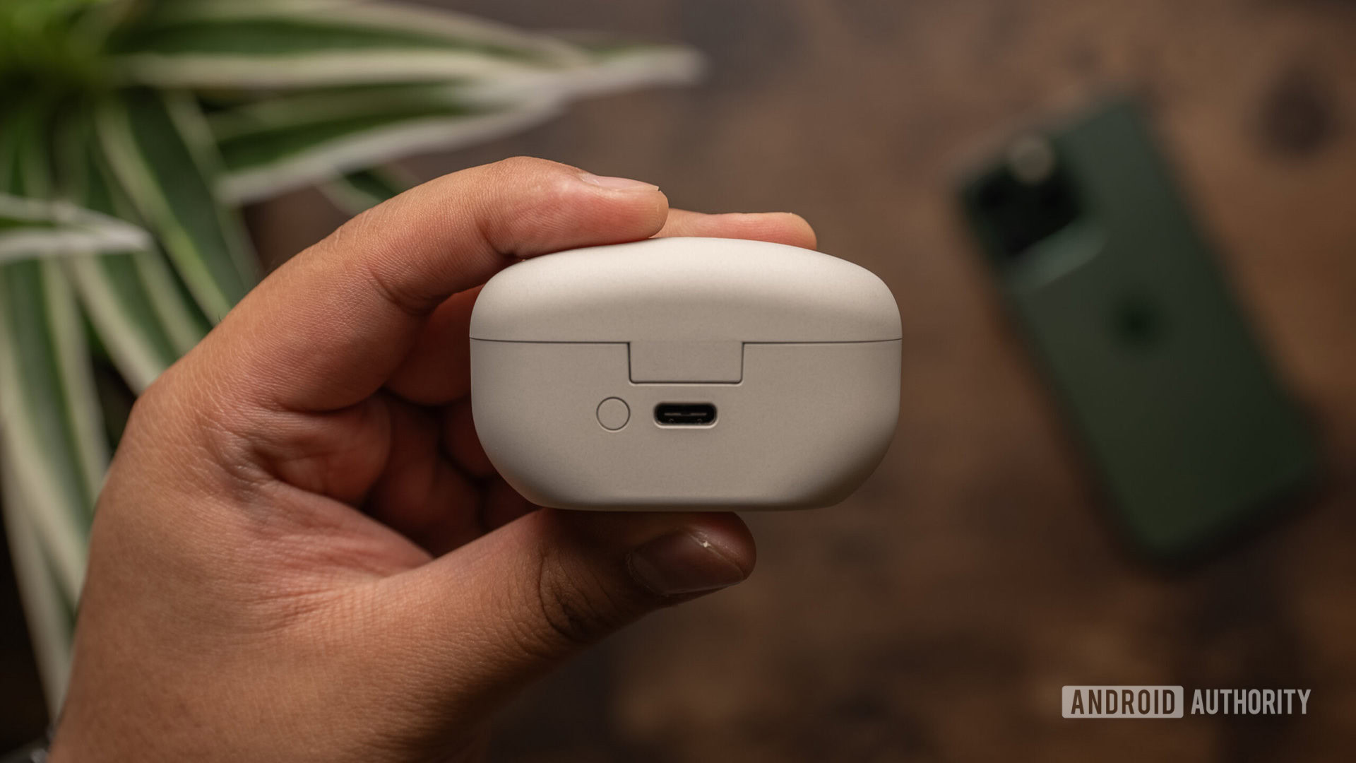 A hand holds the Sony WF 1000XM5 USB-C case.