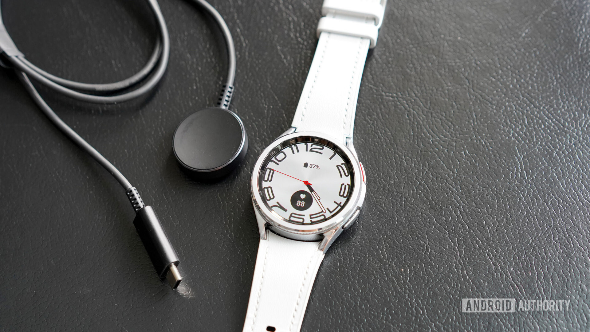 A Samsung Galaxy Watch 6 Classic rests alongside its charger.