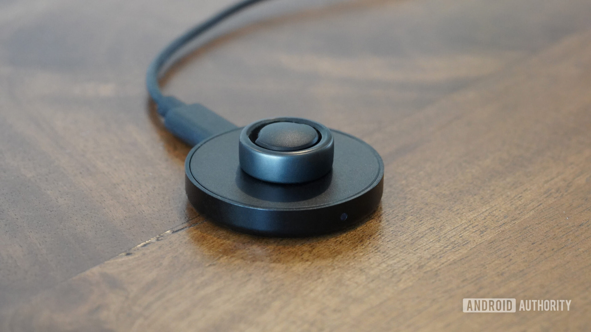 An Oura Ring 3 rests on its charger on a wooden surface.