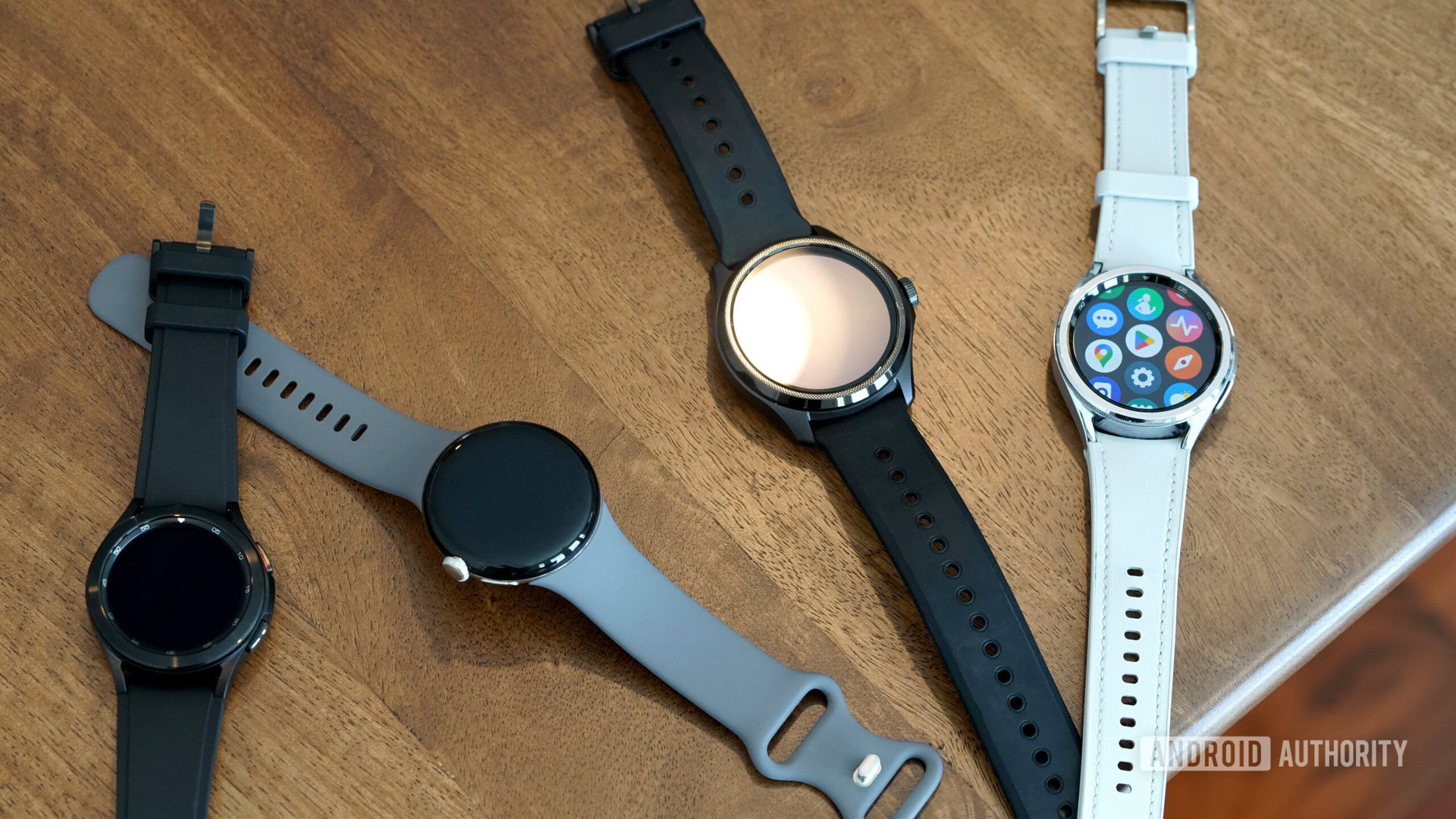 A variety of Wear OS devices rest on a wooden table.