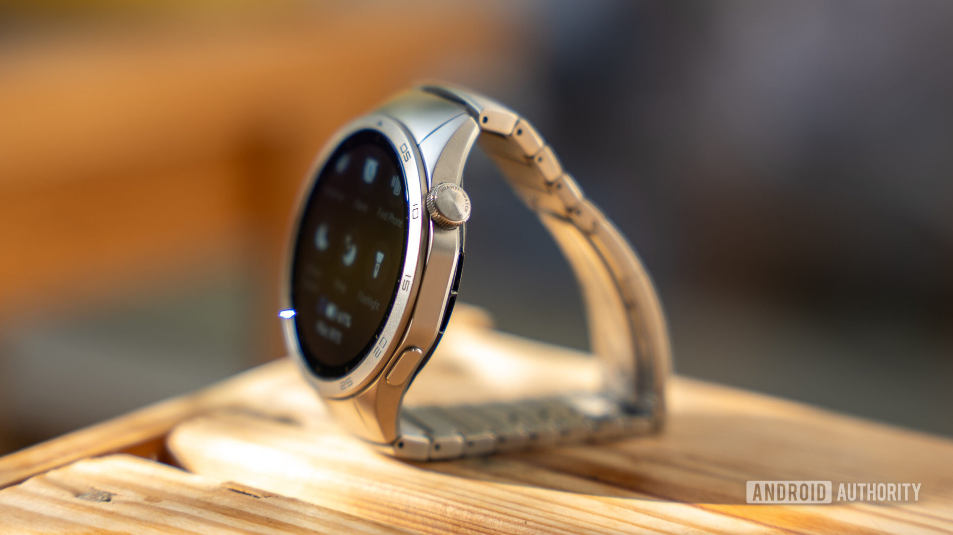 Huawei Watch GT 4 smartwatch on a table showing button, crown, and integrated bracelet design