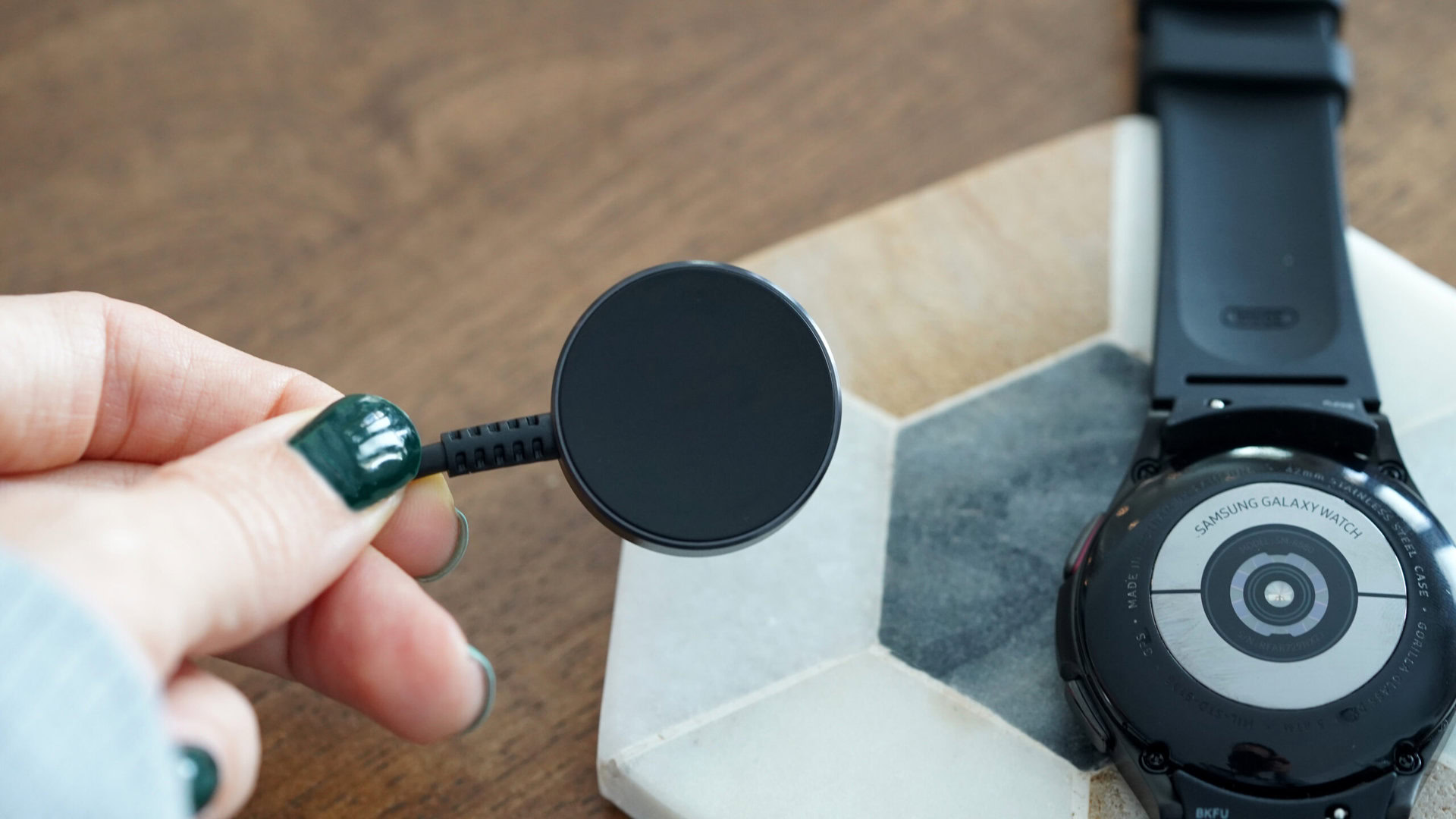 A user inspects their Samsung Galaxy Watch 4 charger for damage.