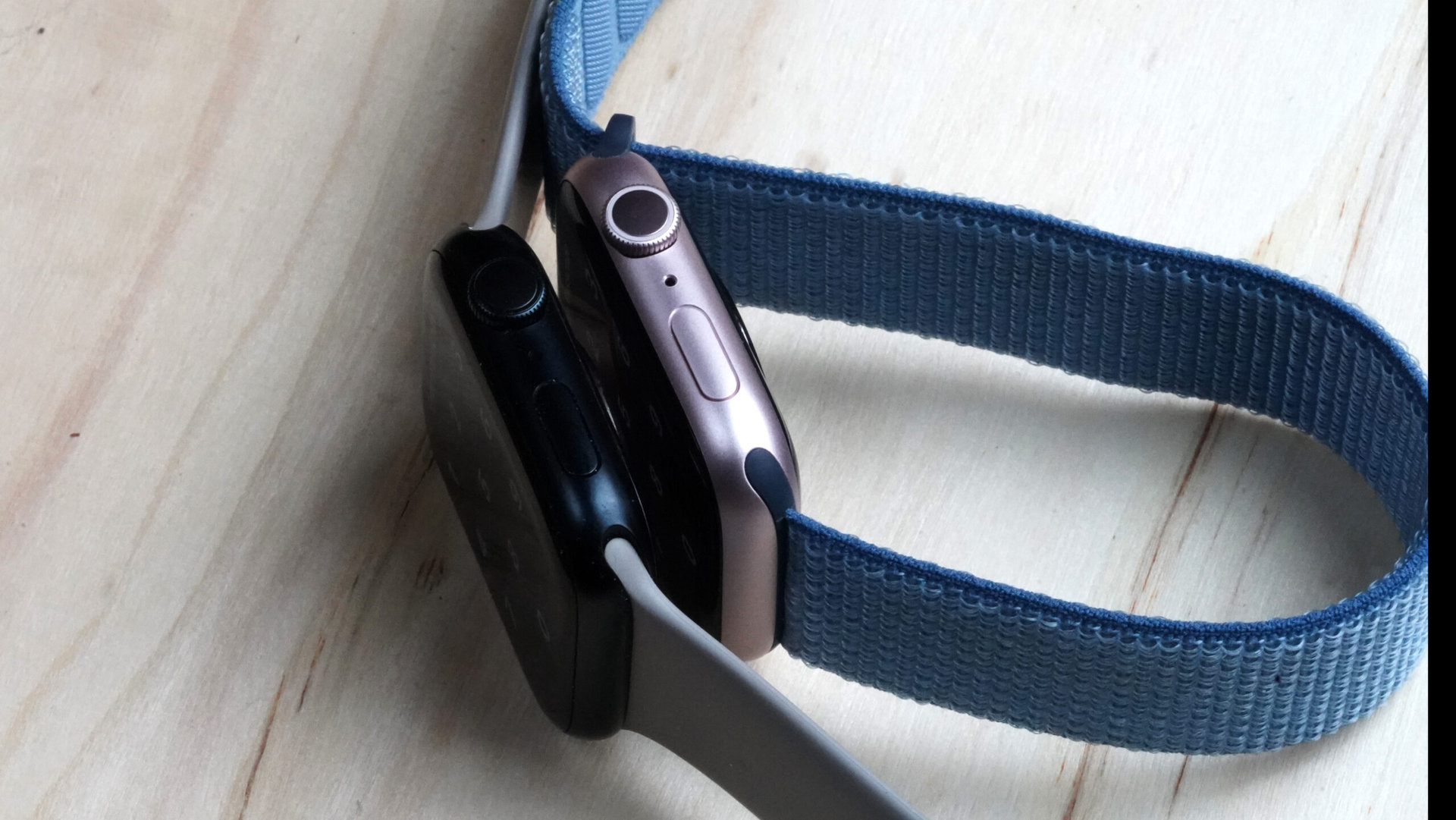 Two Apple Watches rest side by side on their edges.