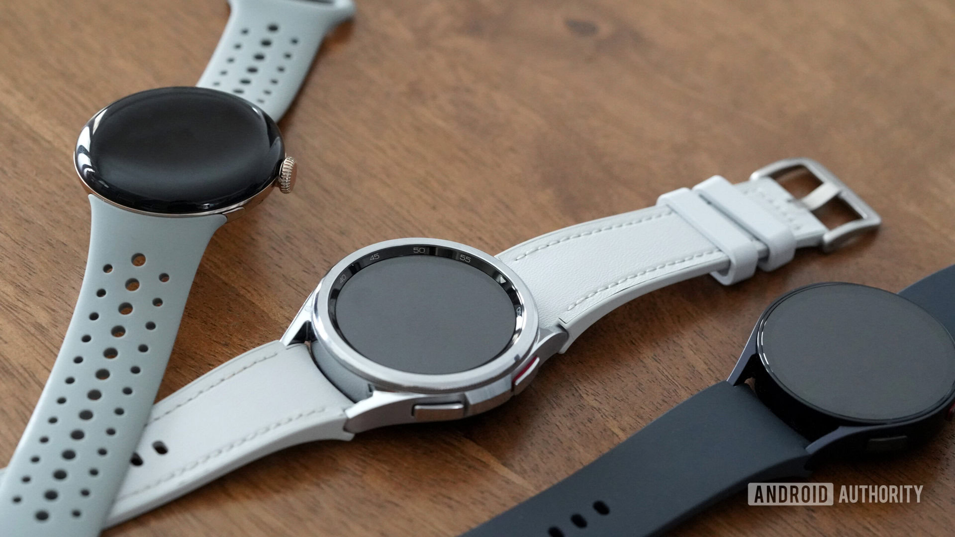 A Galaxy Watch 6, 6 Classic, and Pixel Watch 2 rest on a table.