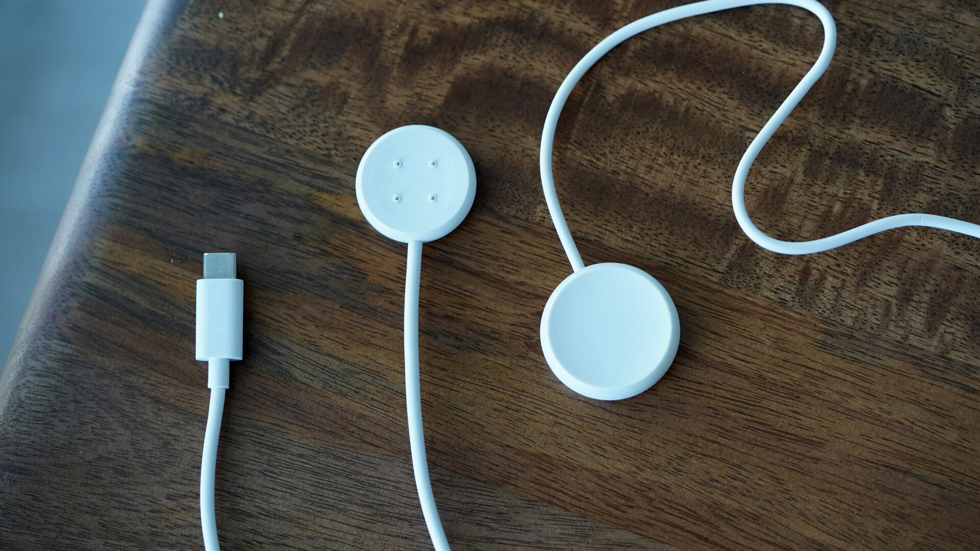 A Pixel Watch 2 charger rests alongside an original Pixel Watch charger.