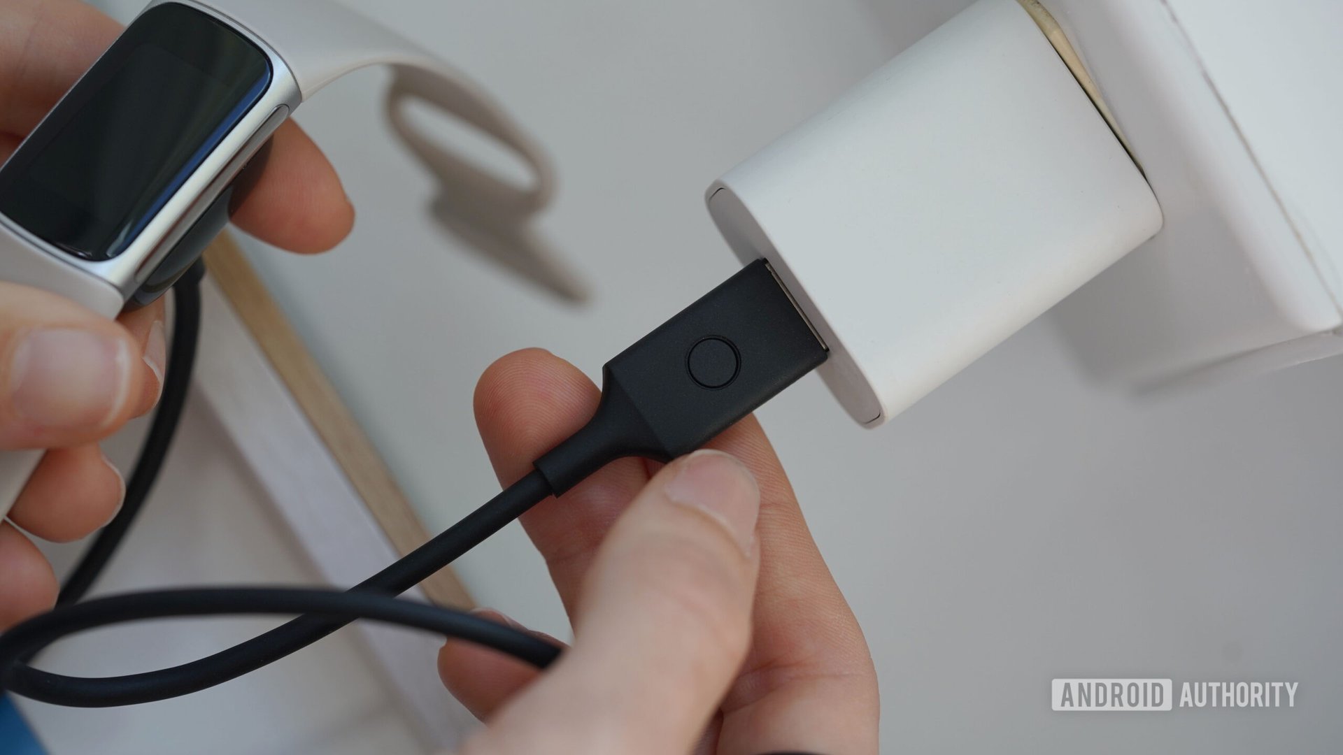 A Fitbit Charge 6 user resets their device via the charging cable.