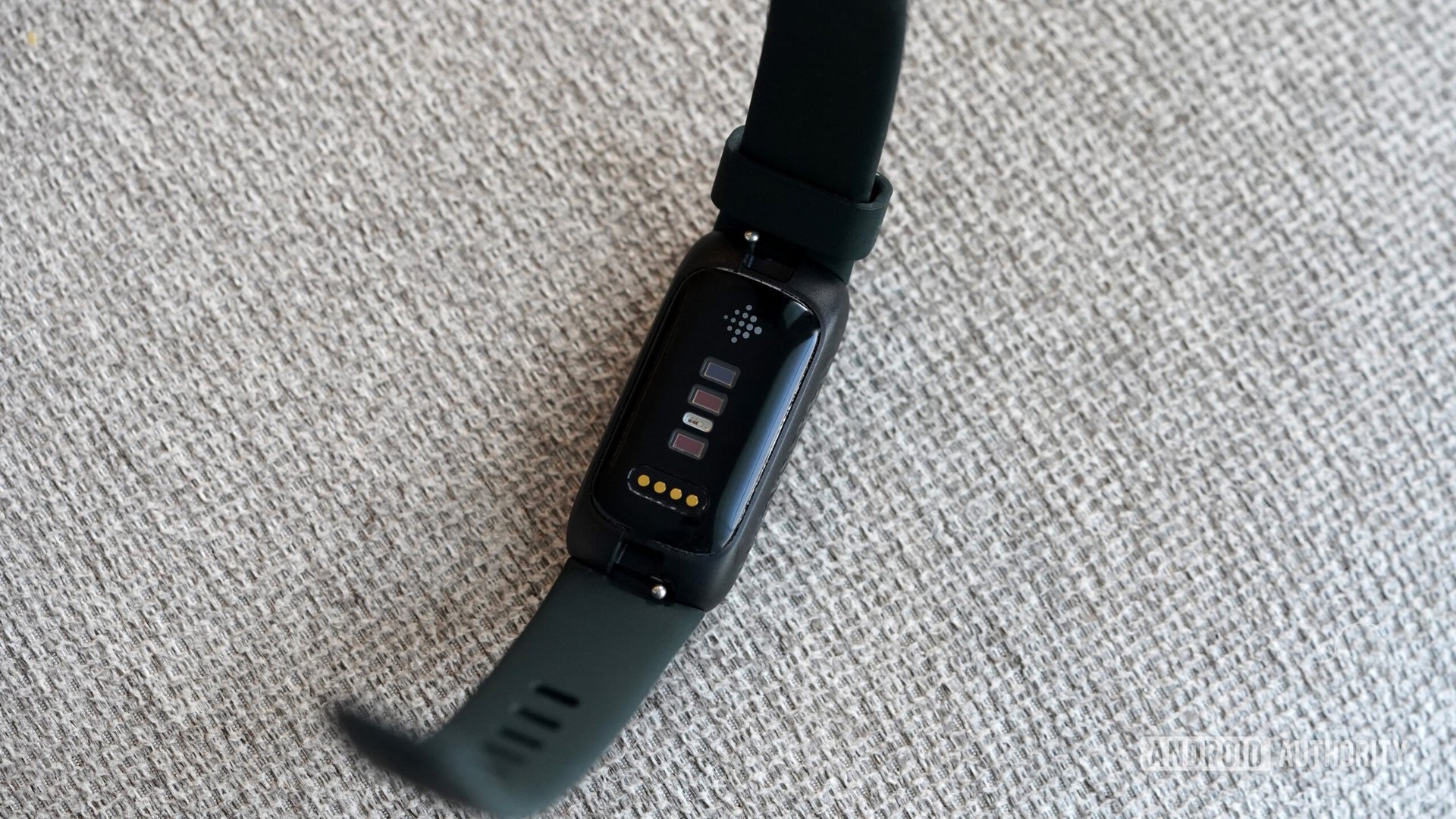 A Fitbit Inspire 3 rests face down displaying its sensors.