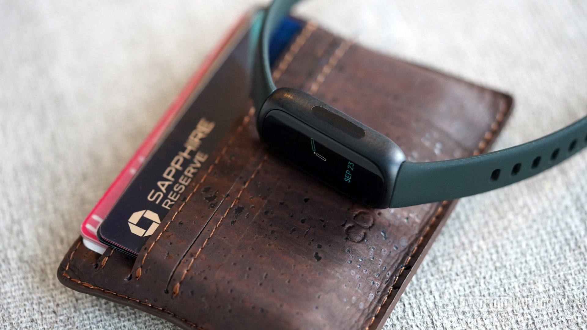 A Fitbit Inspire 3 rests on a users wallet.
