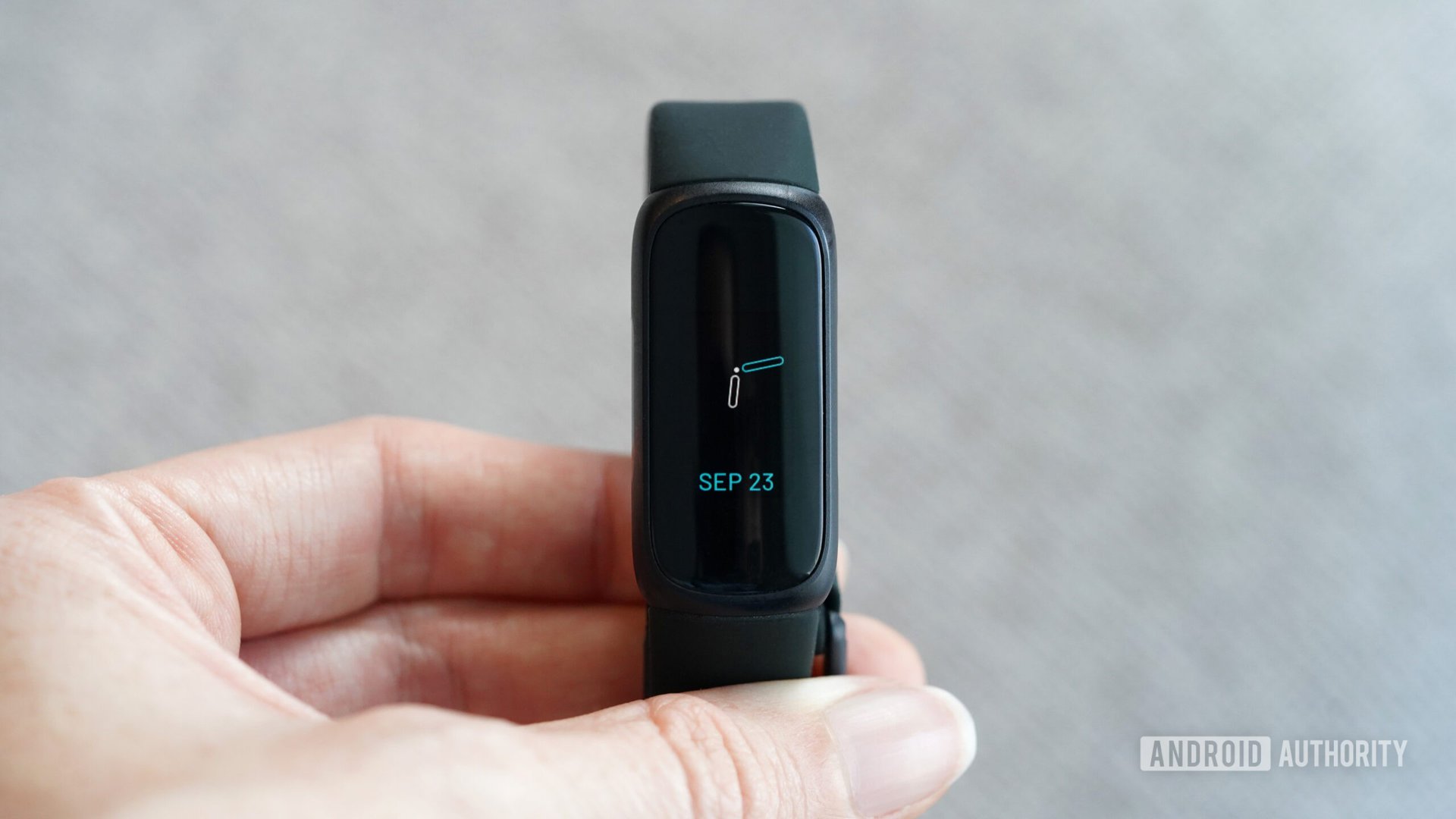 사용자가 Fitbit Inspire 3를 손에 들고 시계 모드를 표시하고 있습니다.