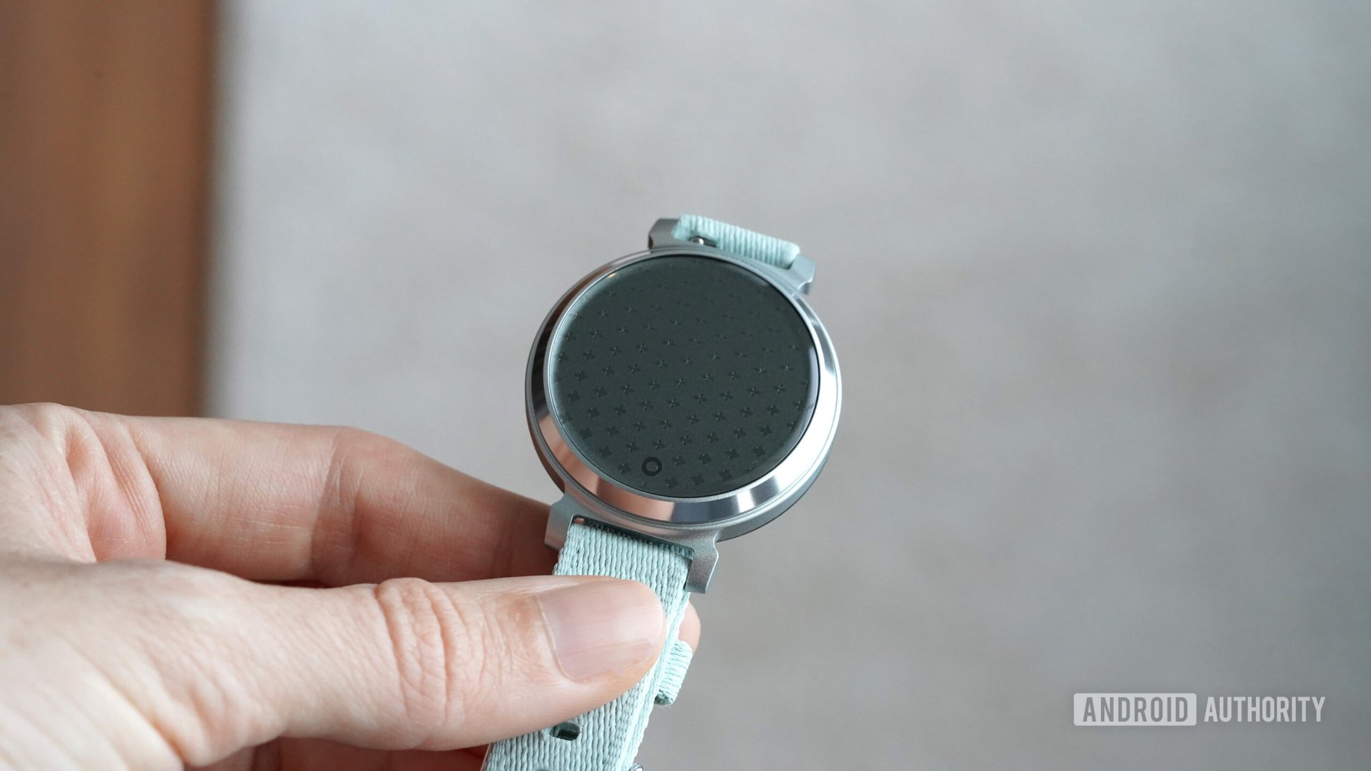A user hold a powered down Garmin Lily 2 in hand, highlighting the device's patterned lens.
