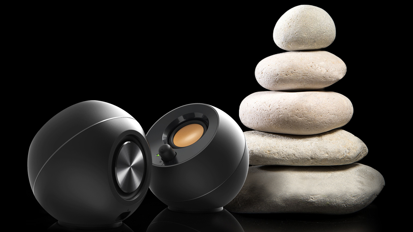Creative Pebble speakers next to actual pebbles