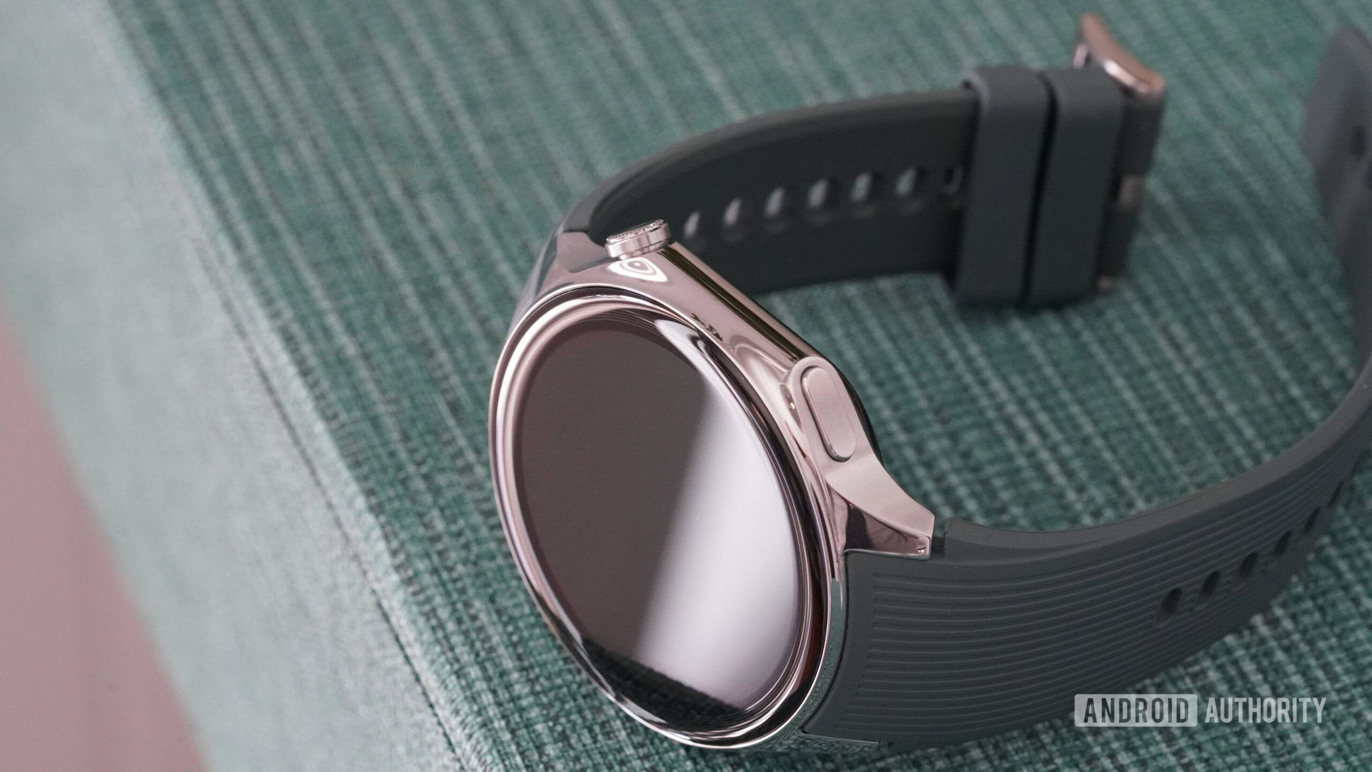 A OnePlus Watch 2 rests on its side, highlighting the device's button and Digital Crown.