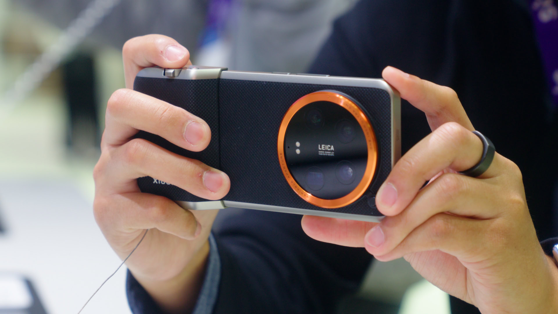 Uchwyt aparatu Xiaomi 14 Ultra w dłoni Pomarańczowa nasadka na gwint filtra