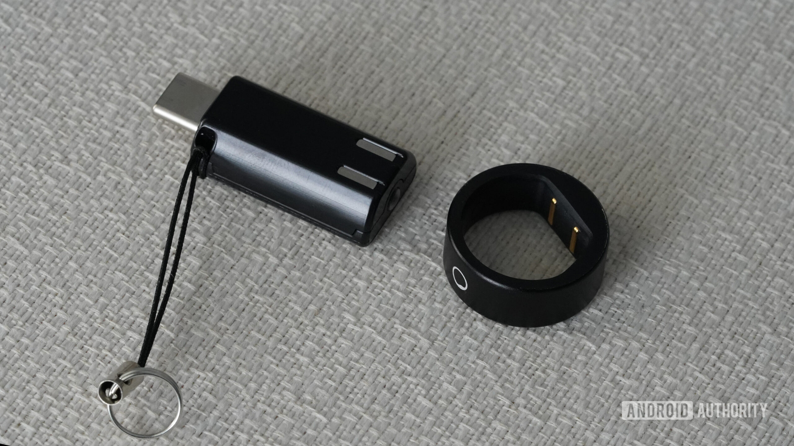 A Circular Ring Slim rests alongside its charger.