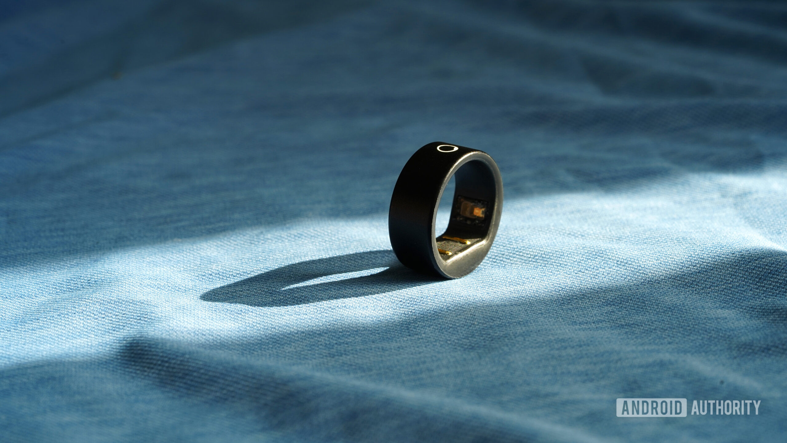 A Circular Ring Slim rests on a blue fabric surface.