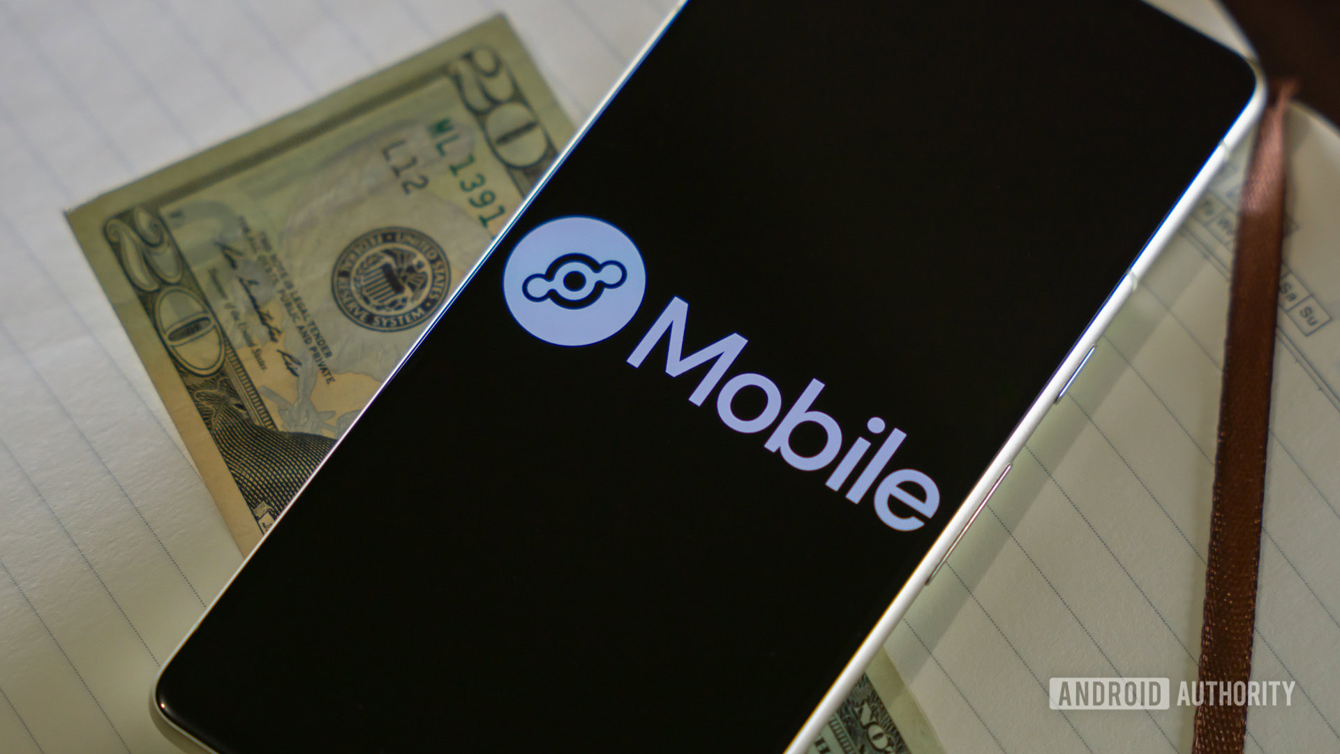 Helium Mobile logo on smartphone next to $20 bill (2) Helium Mobile logo on smartphone next to $20 bill (2)