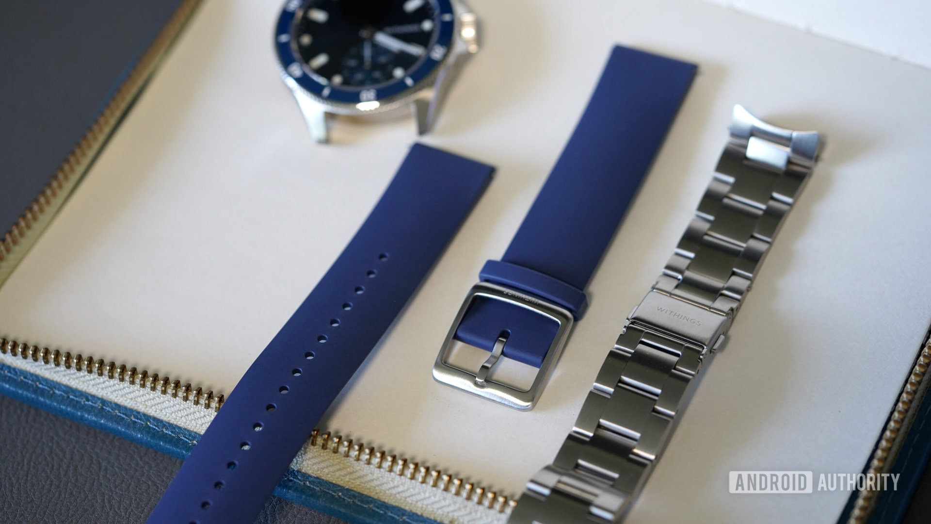 A Withings ScanWatch Nova rests alongside its metal and fleuroelastomer band.