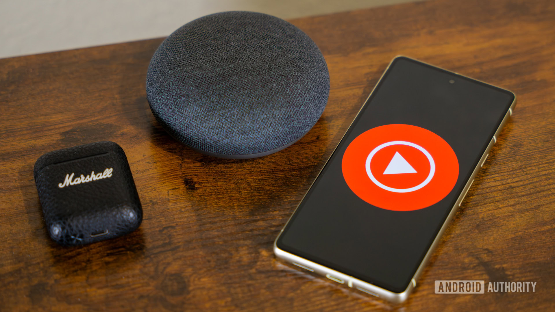 YouTube Music logo on smartphone, next to headphones and Nest Mini (4)