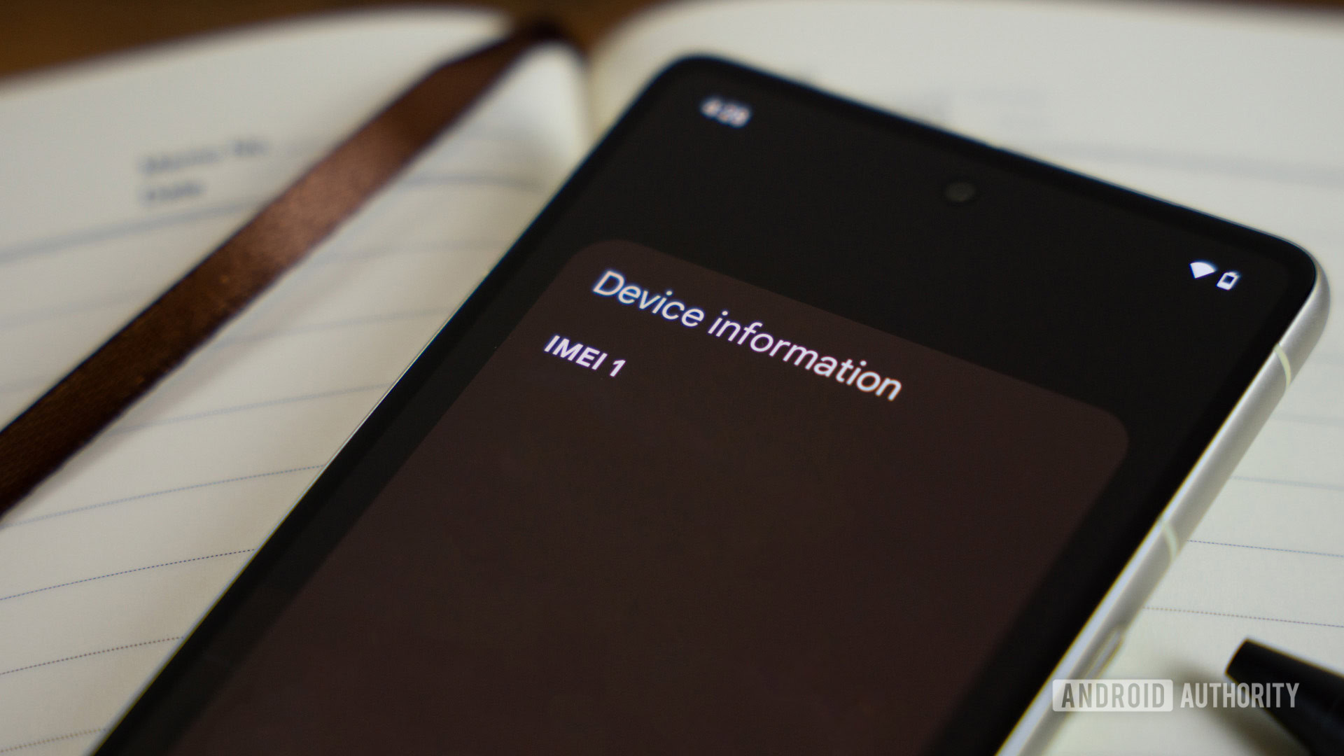 IMEI page on smartphone, laying on notebook next to pen stock photo