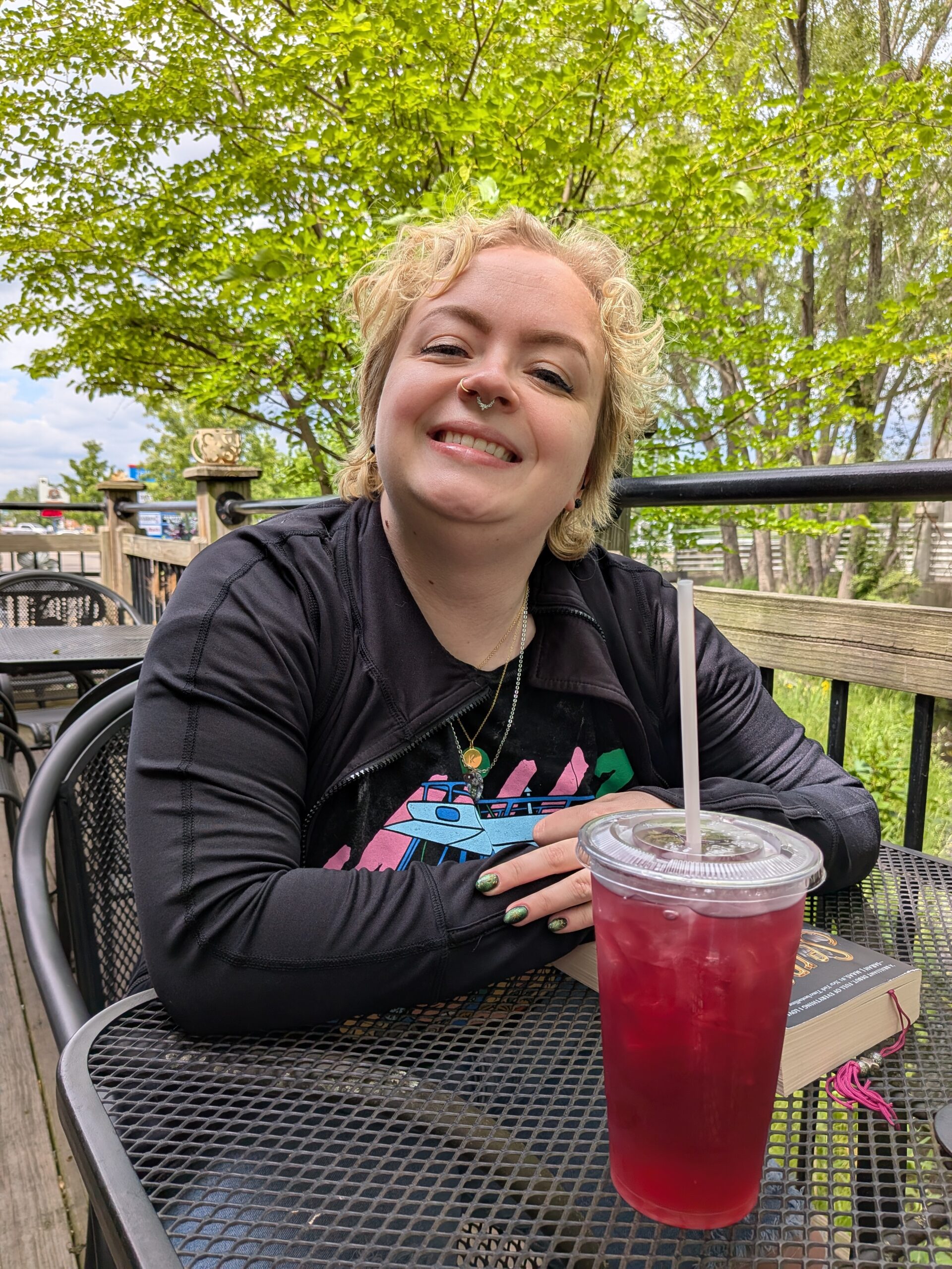 Photo of a person sitting at a table with iced tea and a book, taken with the Google Pixel 9a.