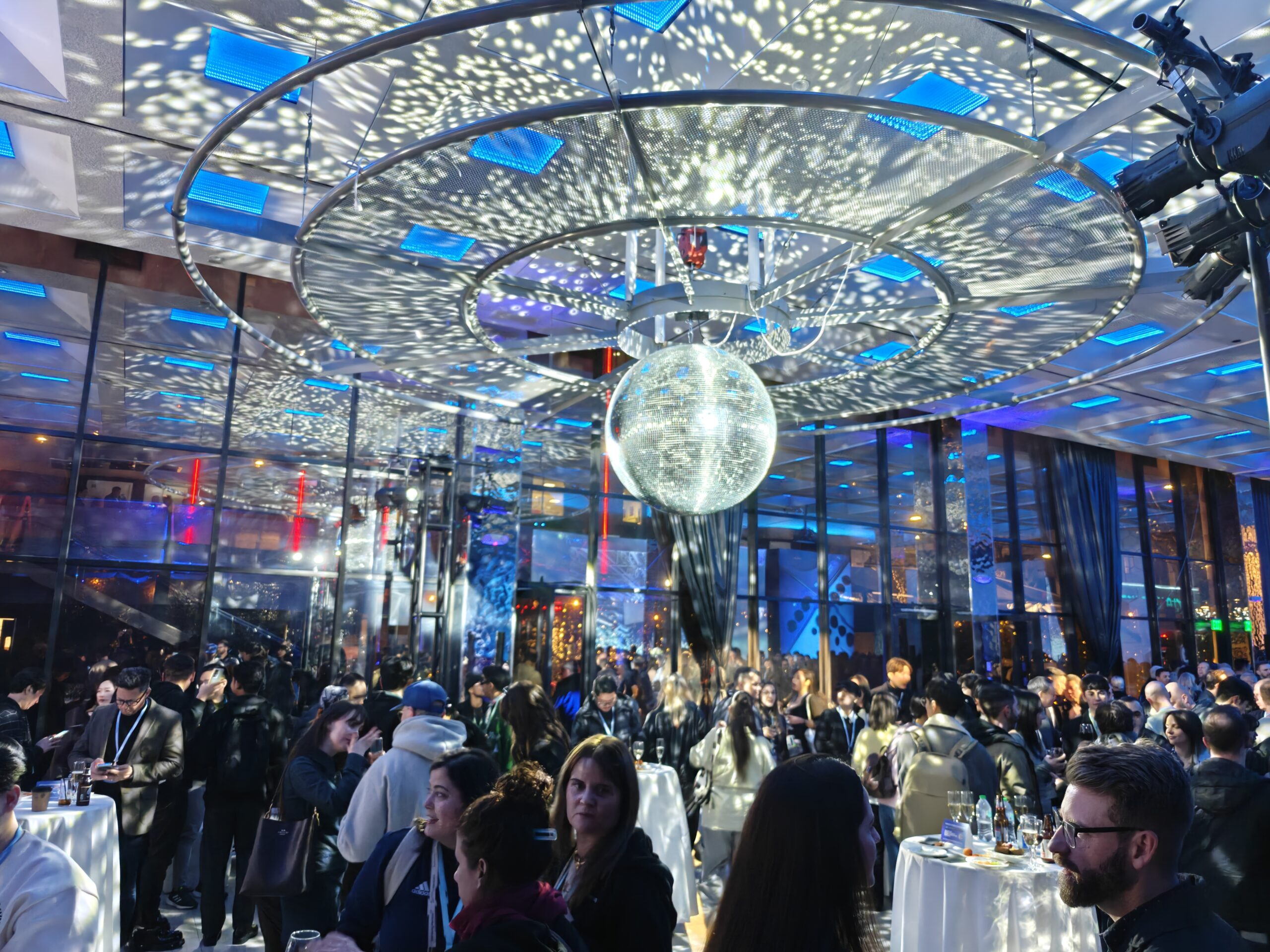 A photo of a packed bar with a disco ball hanging from the ceiling, taken with the OnePlus 13.