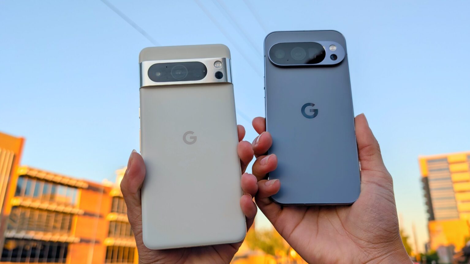 Google Pixel 8 Pro and Google Pixel 10 Pro held in the air with a blue sky in the background