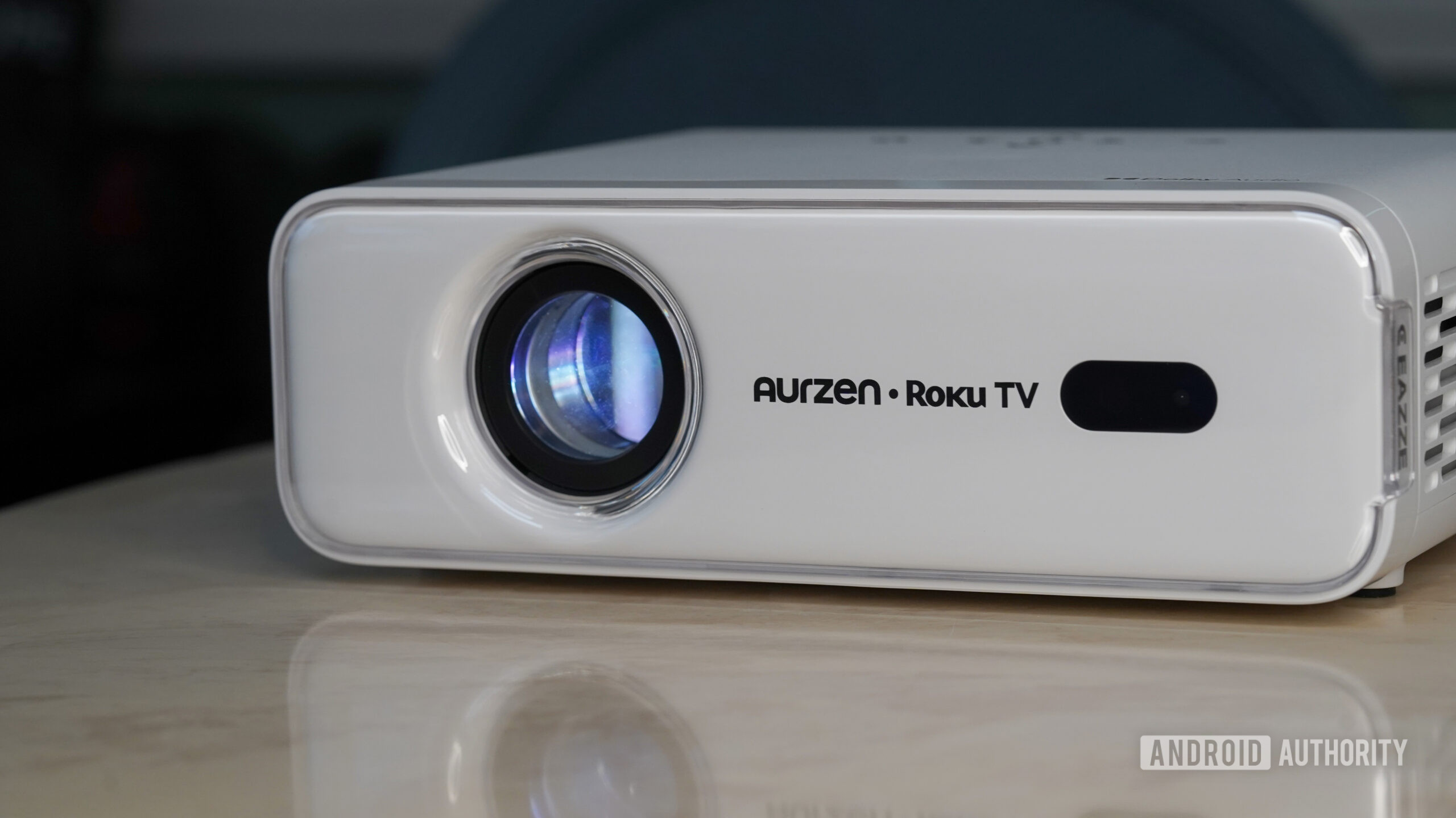 The Aurzen Roku TV EAZZE D1R rests on a stone surface.