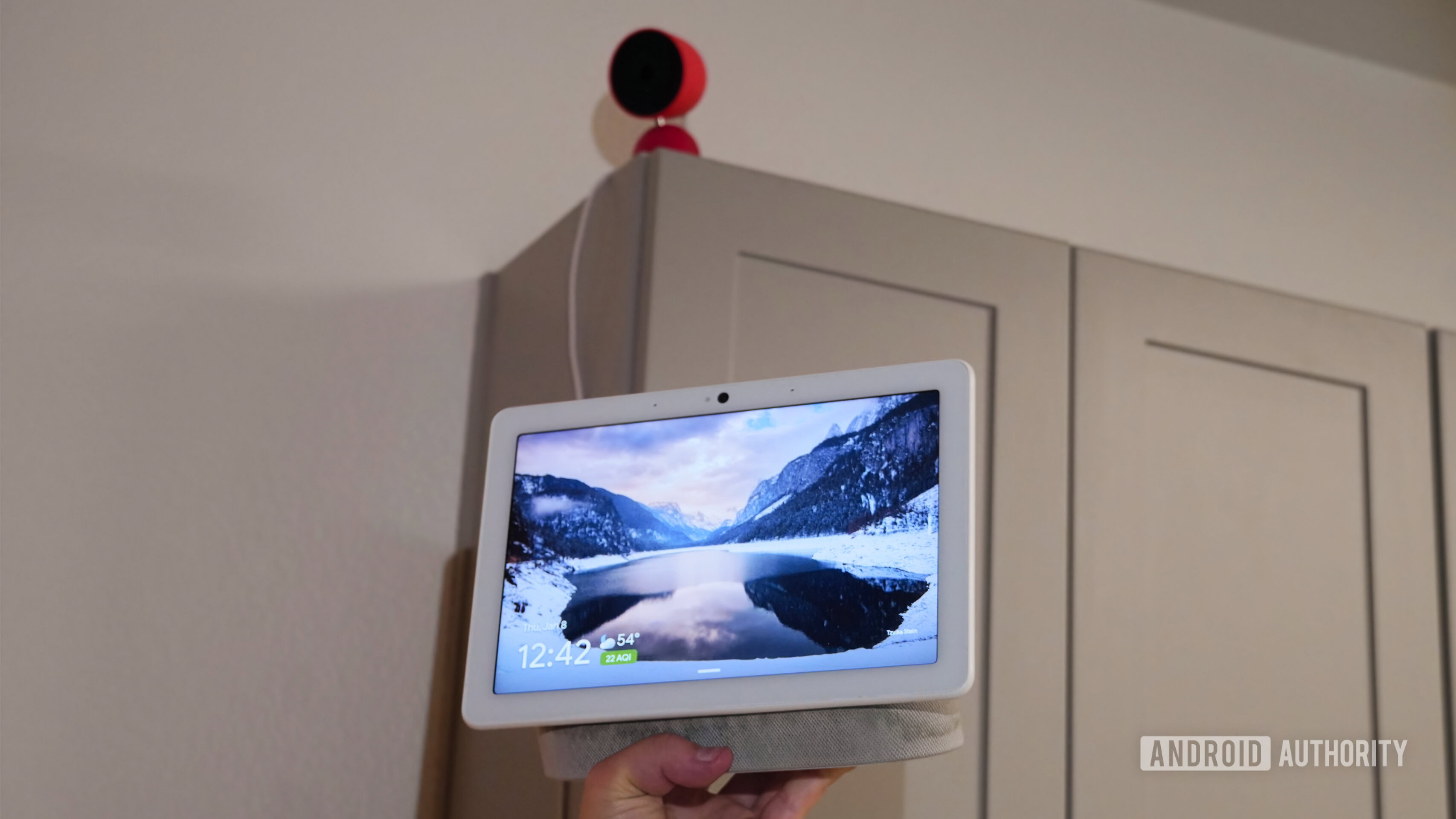 An old Nest Hub Max held up near a new Nest Cam with updated colorways.