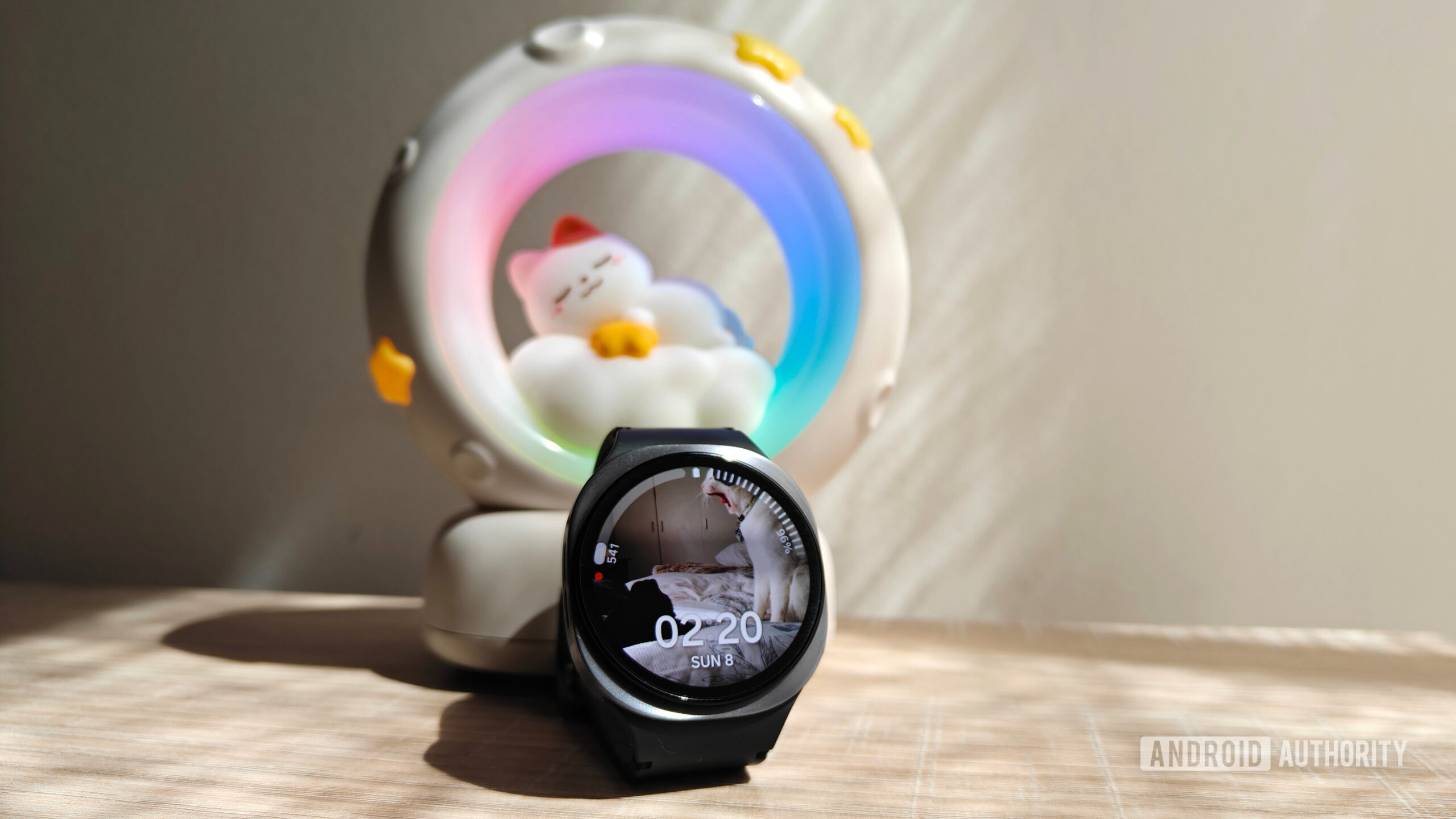 a galaxy watch 8 in front of a night light with a cat sleeping on a moon a galaxy watch 8 in front of a night light with a cat sleeping on a moon
