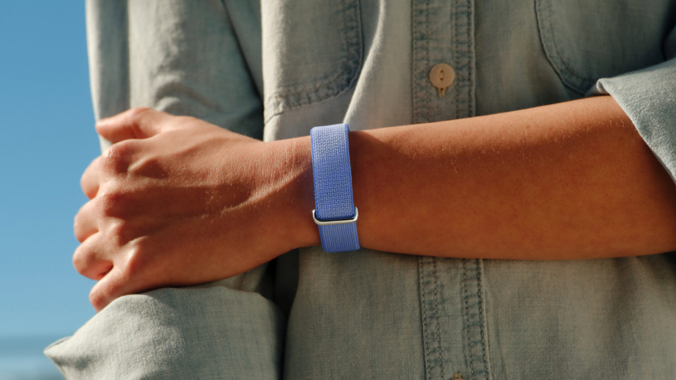A lifestyle photo of someone wearing the Google Fitbit Air in its Lavender color.