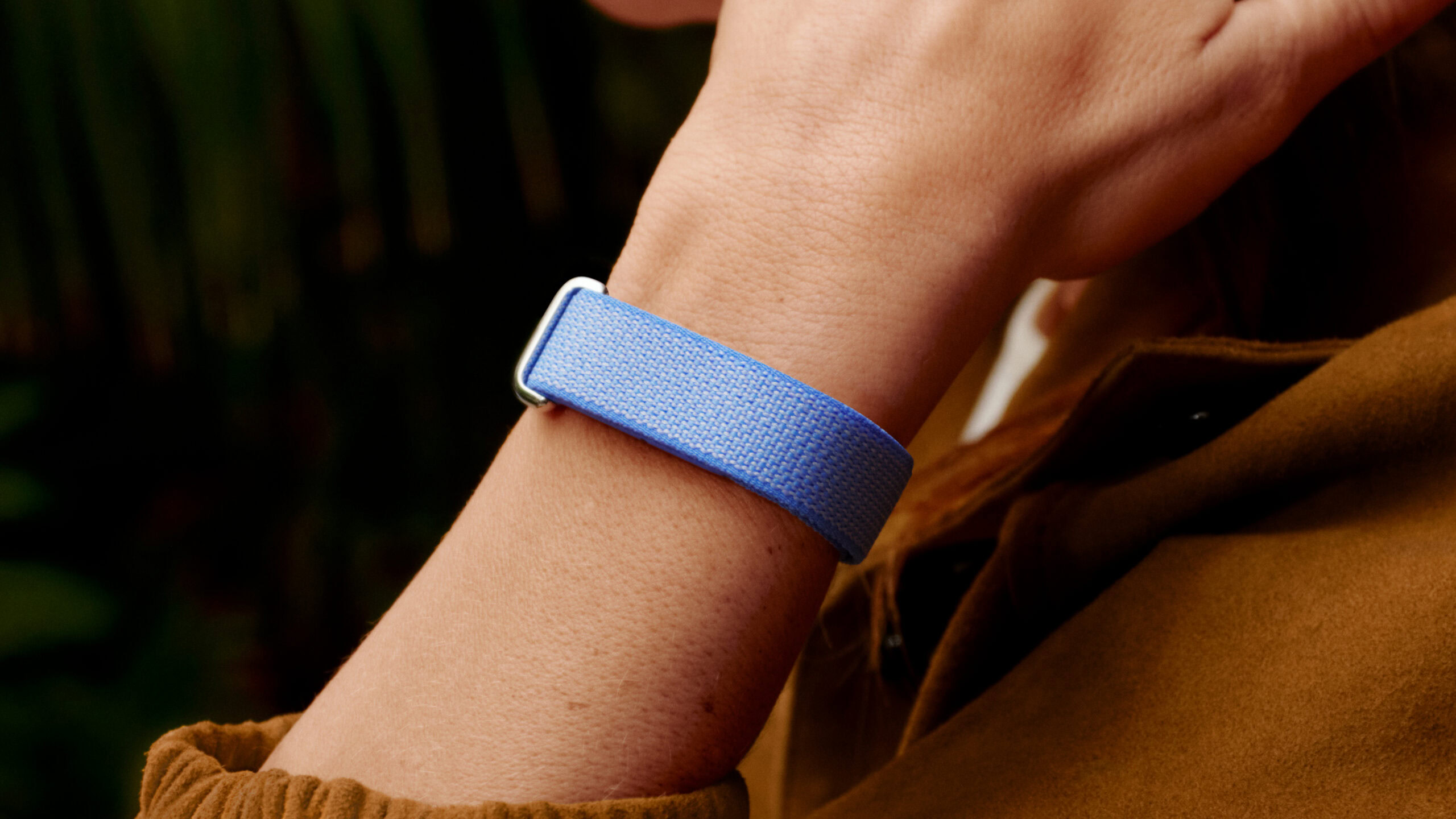 A lifestyle photo of someone wearing the Google Fitbit Air in its lavender band color.