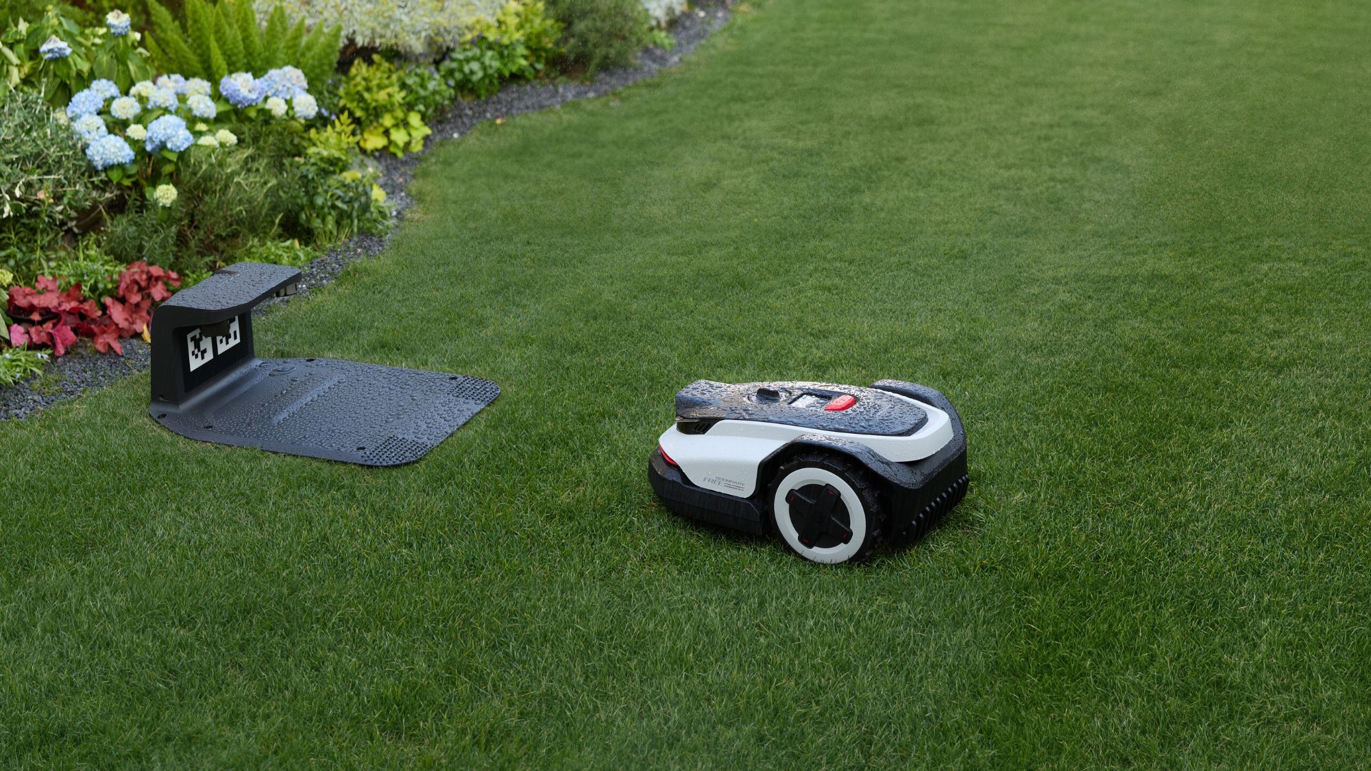 RockNeo Q110H robotic lawnmower near its charging station RockNeo Q110H robotic lawnmower near its charging station