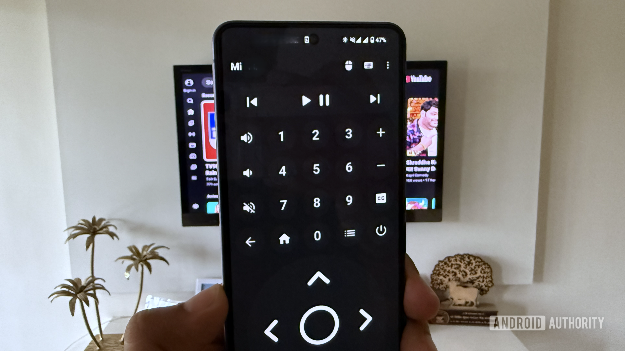Android phone in hand showing a Bluetooth Remote app in front of a TV Android phone in hand showing a Bluetooth Remote app in front of a TV