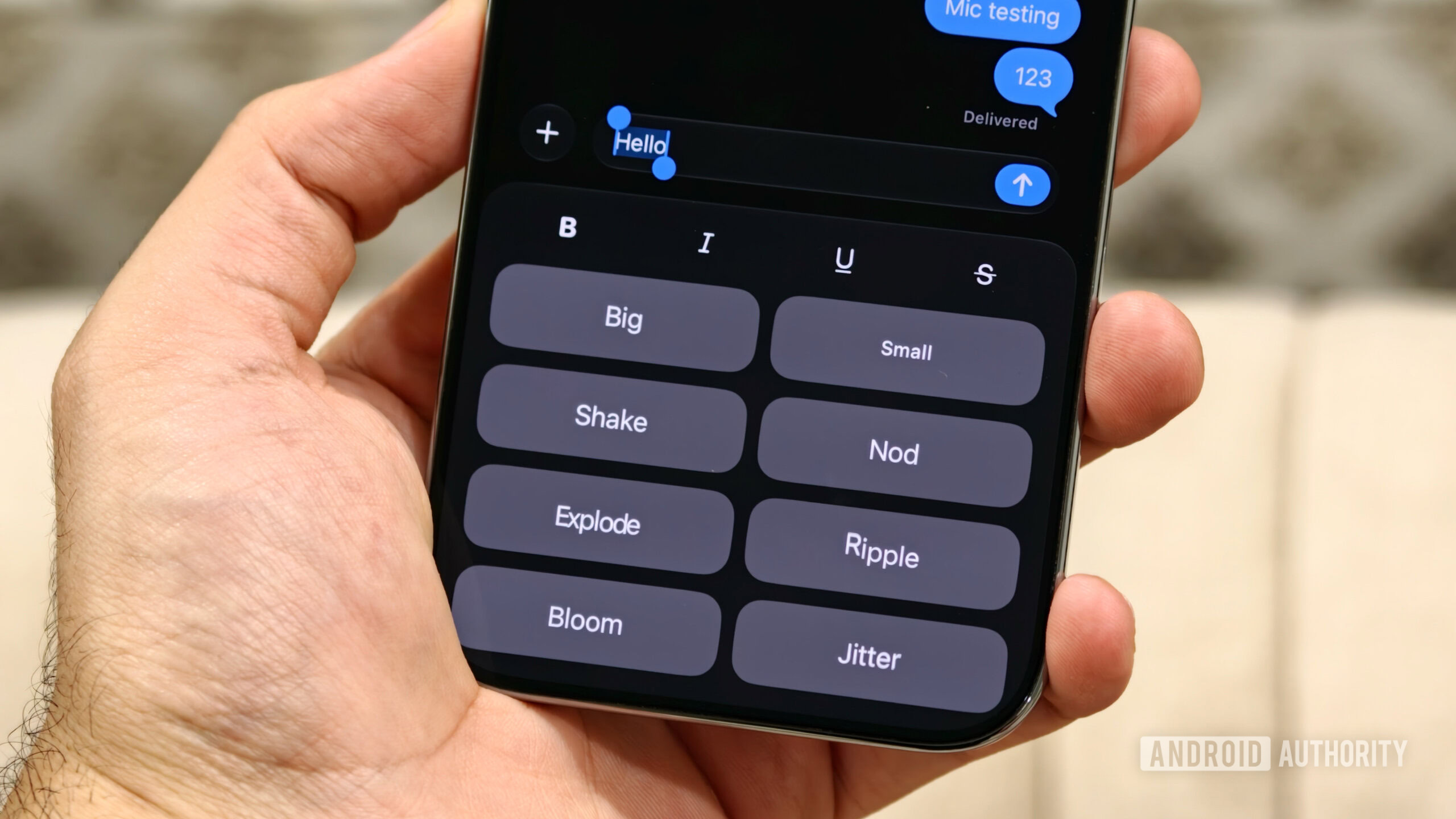 iphone messages text effect A hand holding an iPhone showing the iMessage text effects menu with options like Big, Shake, Explode, and Ripple