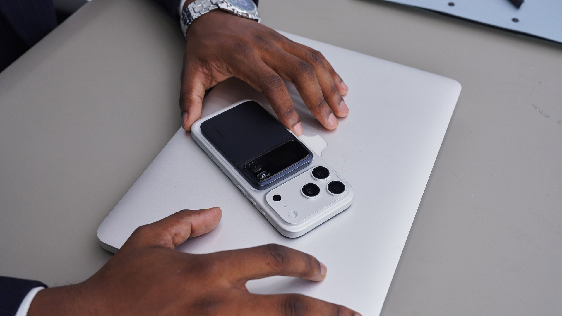 Comu Action Pro AI assistant Comu-Action-Pro-AI-assistant-magnetically-attached-to-the-back-of-a-smartphone-resting-on-a-closed-laptop
