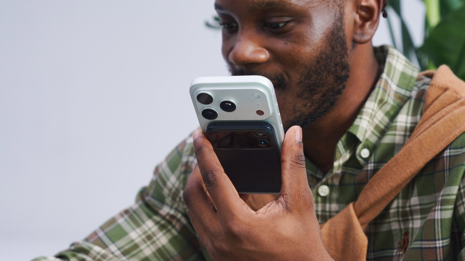 A smartphone with a rear mounted Comu Action Pro AI voice recorder Man-holding-a-smartphone-with-a-rear-mounted-Comu-Action-Pro-AI-voice-recorder-while-speaking