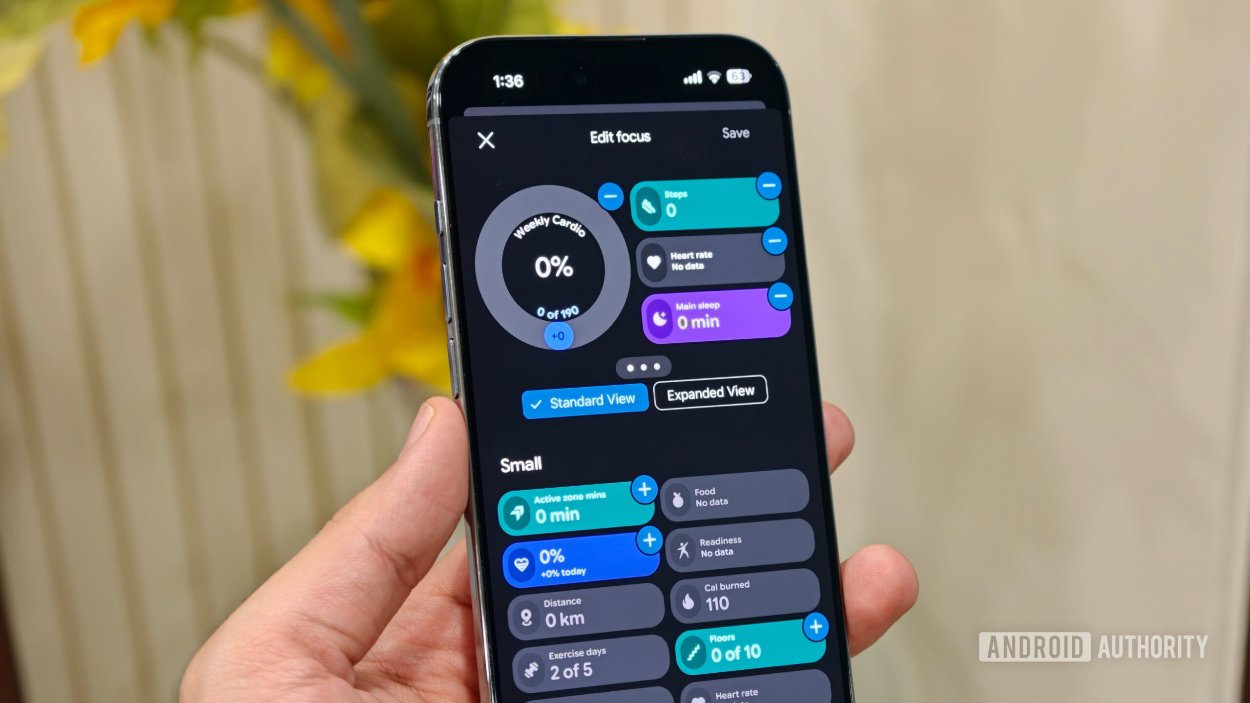 A person holding a smartphone showing the "Edit focus" customization screen in Google Health app with widgets for cardio, steps, and sleep