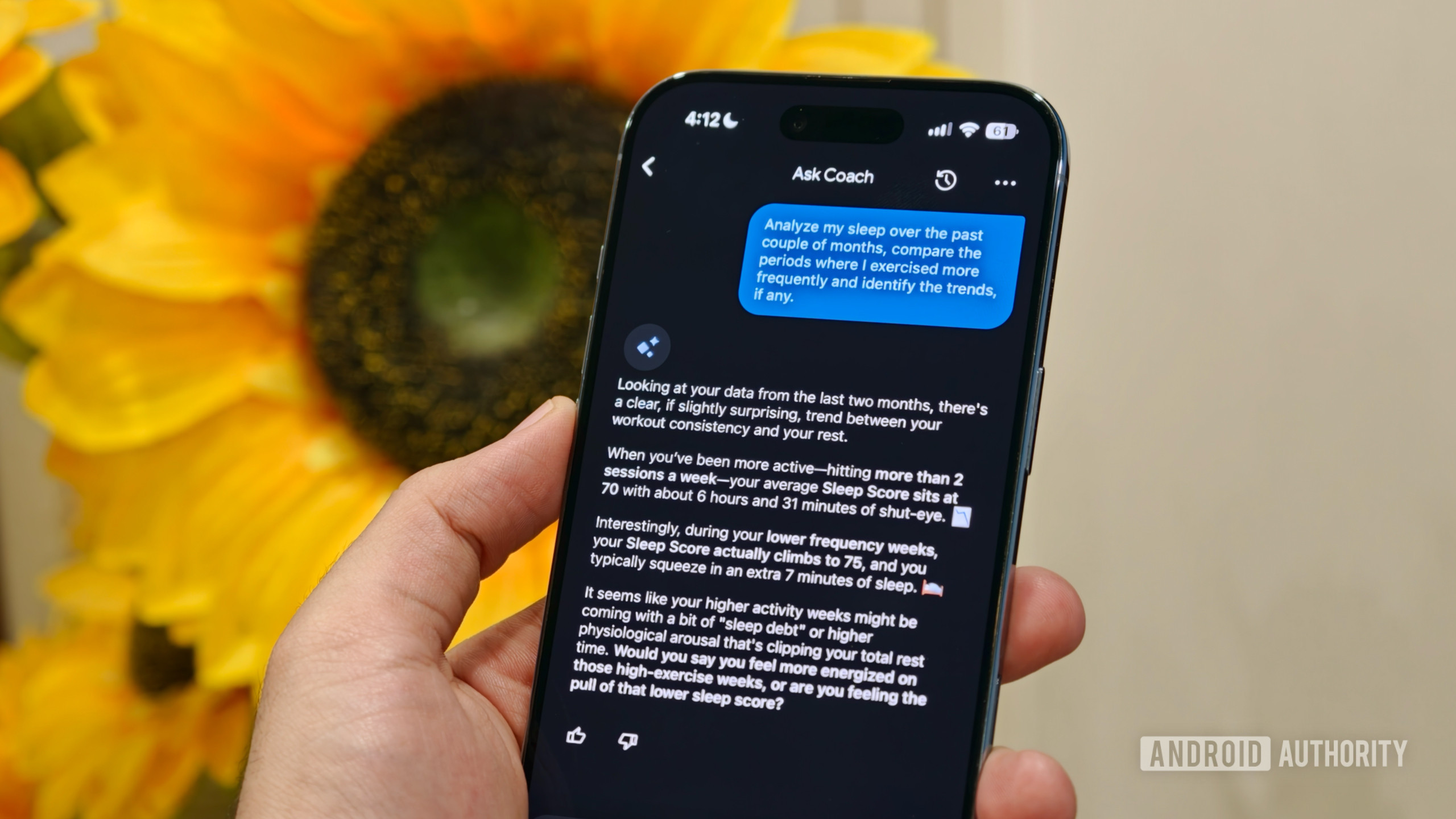 A hand holding a smartphone displaying the "Ask Coach" AI chat interface in Google Health analyzing user sleep and workout trends