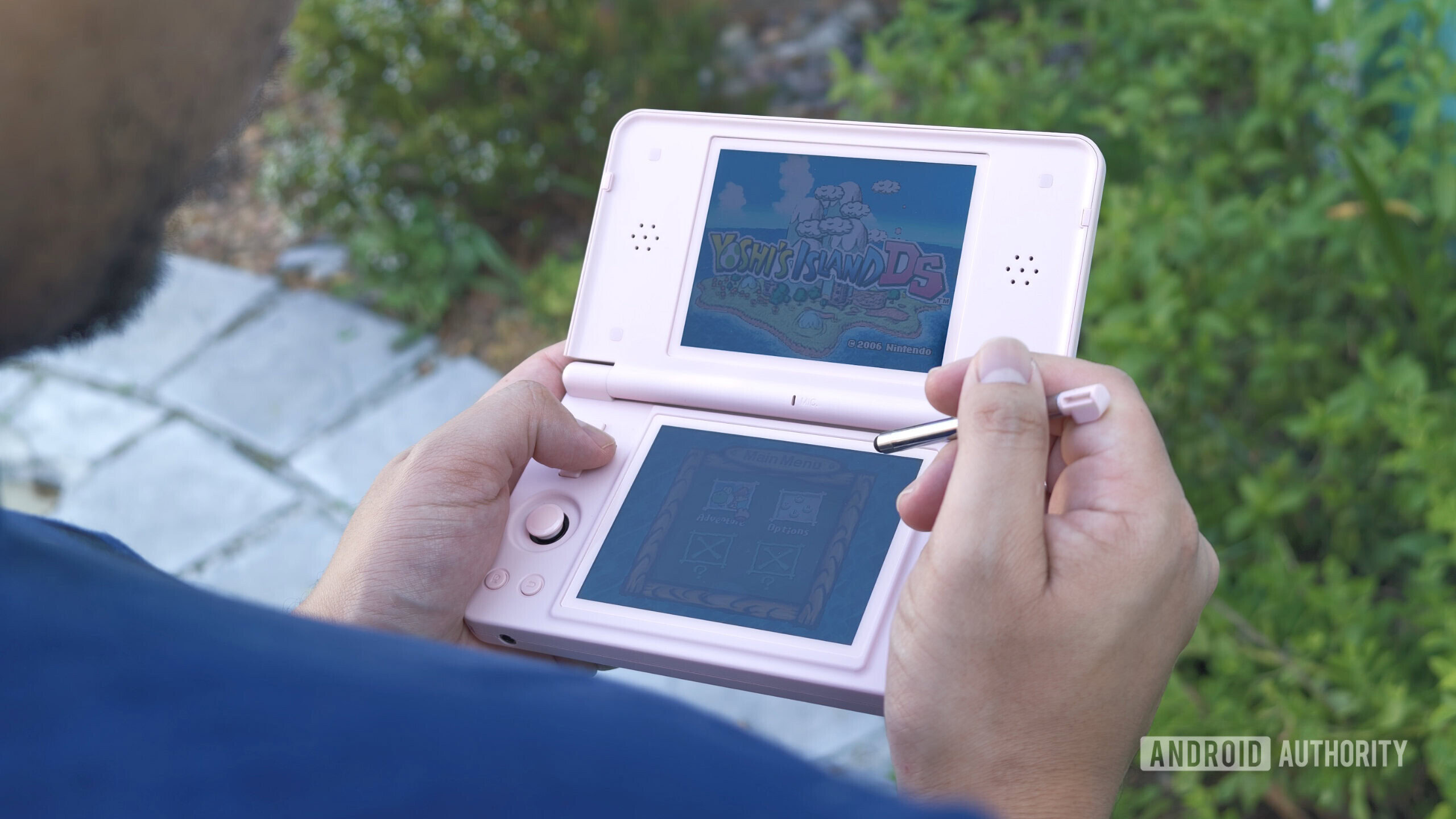 ANBERNIC RG DS Plus in hand showing stylus and screens ANBERNIC RG DS Plus in hand showing stylus and screens