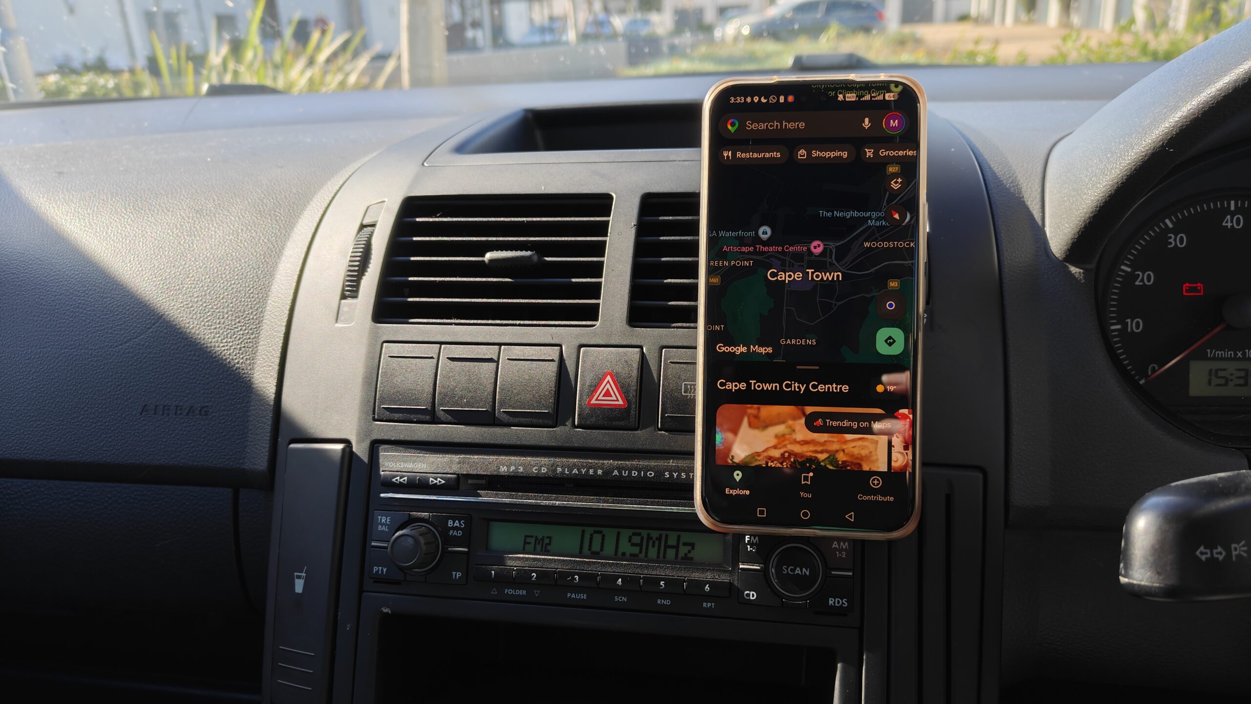 a phone mounted on a car dashboard with a radio showing underneath a phone mounted on a car dashboard with a radio showing underneath