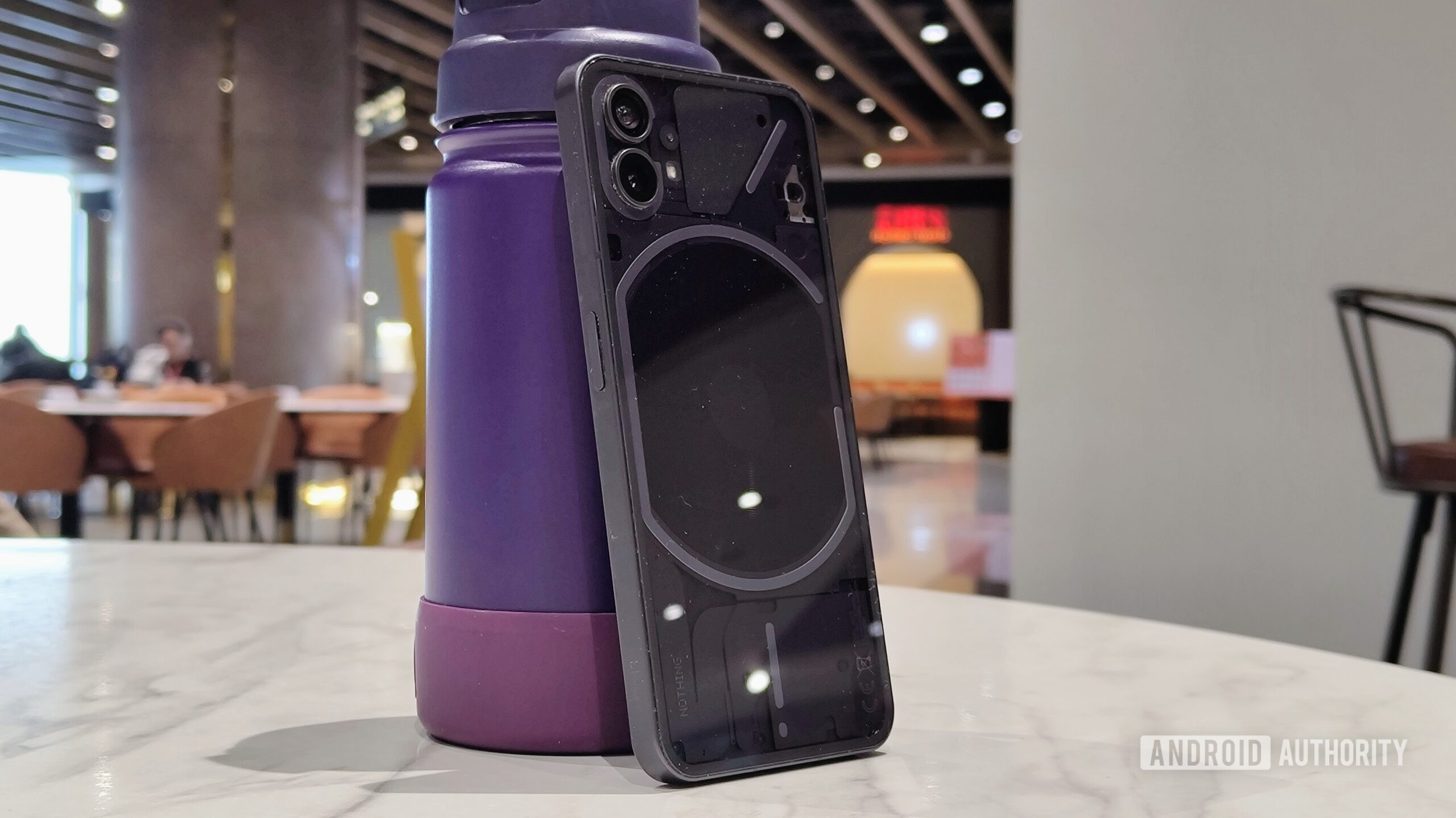 Nothing Phone 1 standing upright against a water bottle.