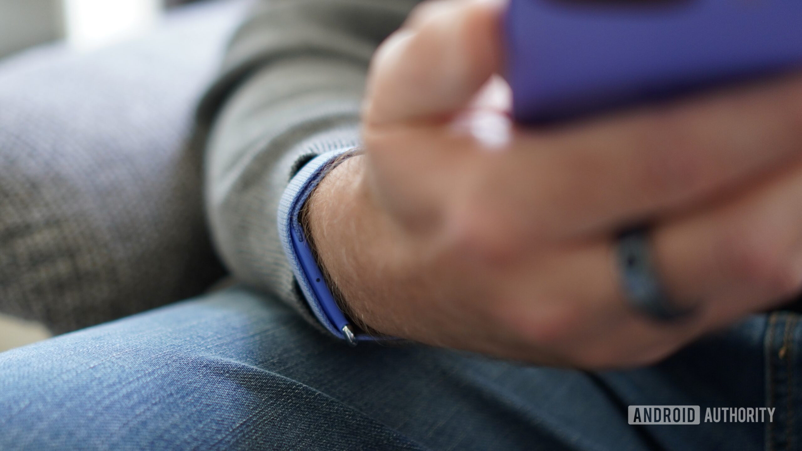 A person wearing a Fitbit Air and holding a phone.